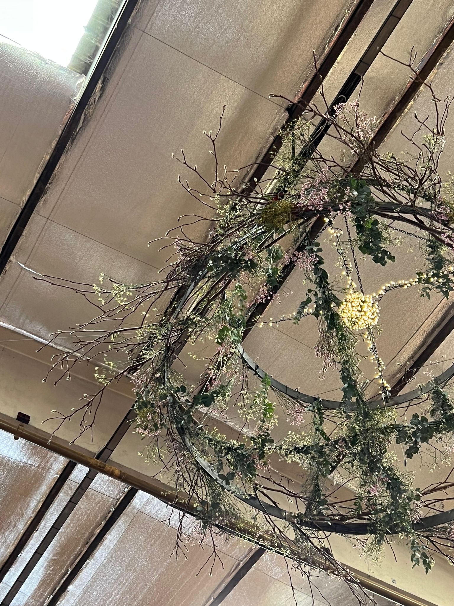 Decorative floral chandelier in spring colours on a high ceiling with a neutral background
