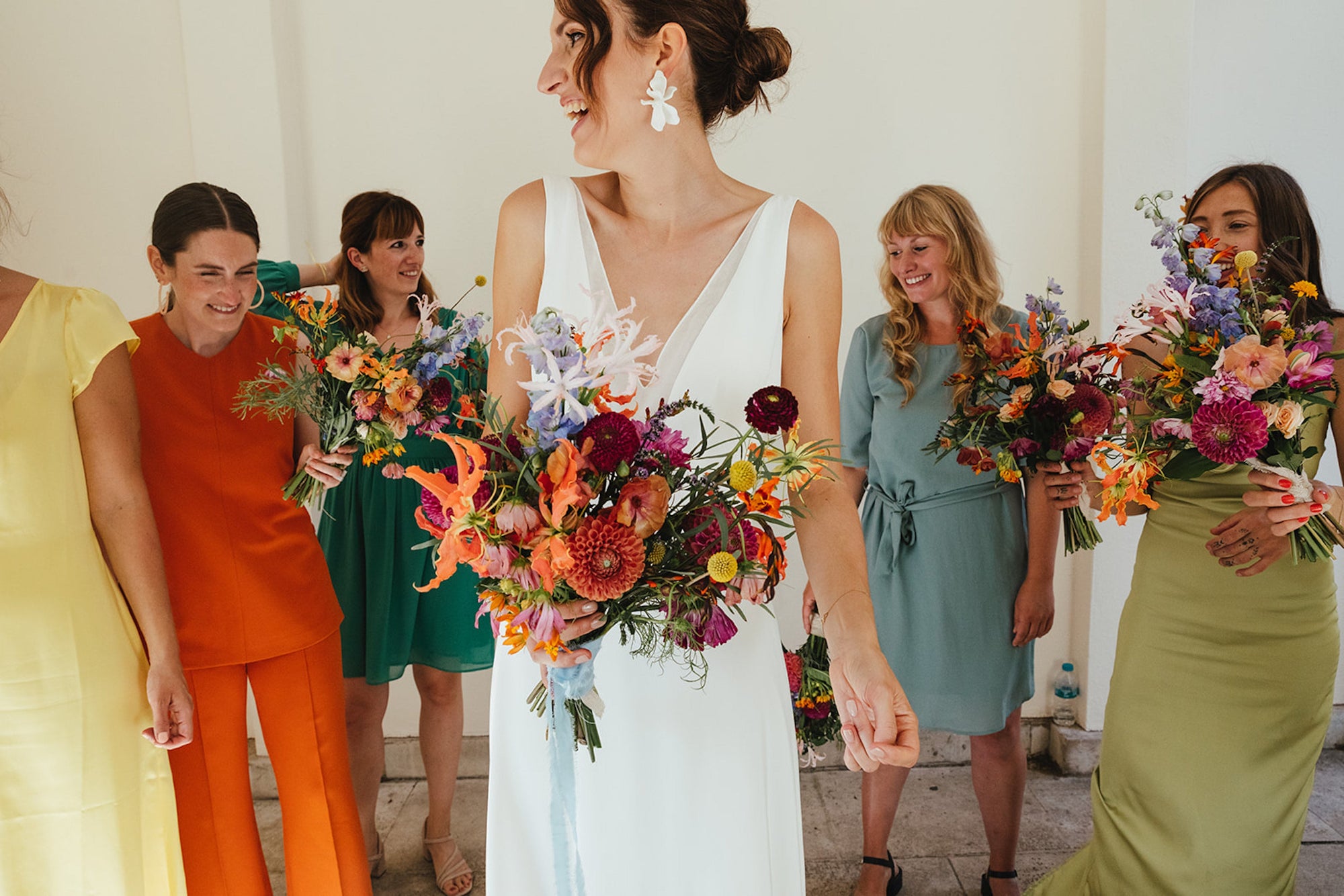 Bride with colourful bouquet surrounded by bridesmaids in colourful dresses. Summer bridal bouquet of dahlia, Nerrine,Gloriosa lily and Crocosmia