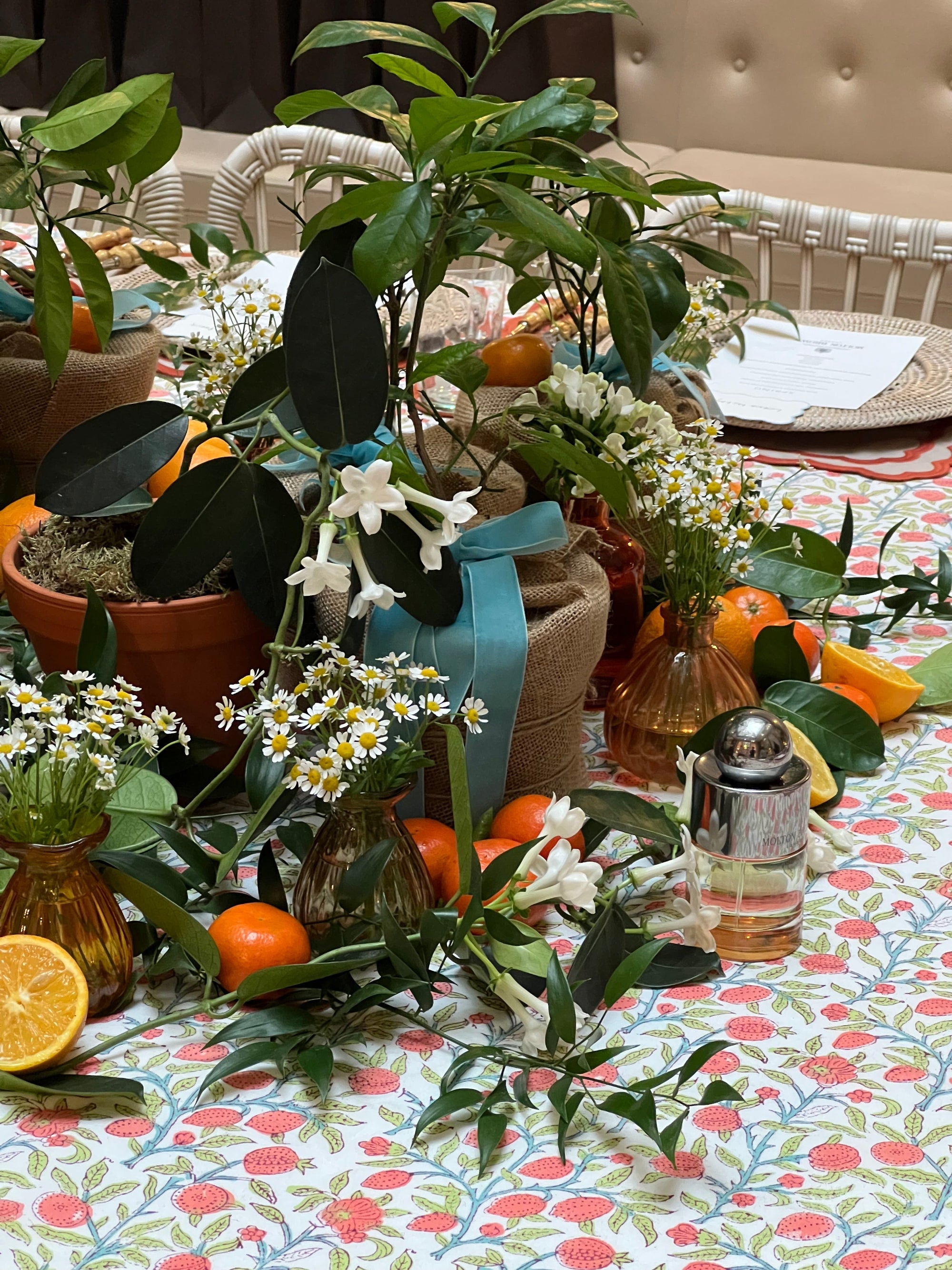 Decorative floral styling for perfume launch with citrus fruits and scented flowers to form a central table display