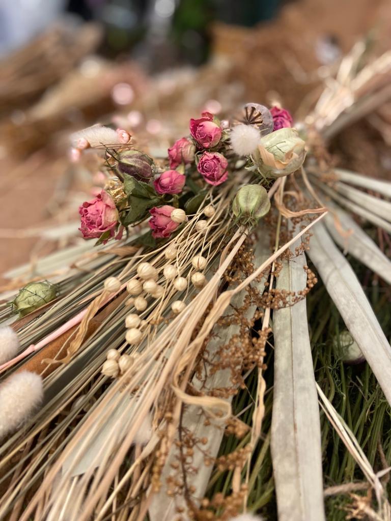 Dried flowers and herbs with pink rose buds and green leaves on a blurred background