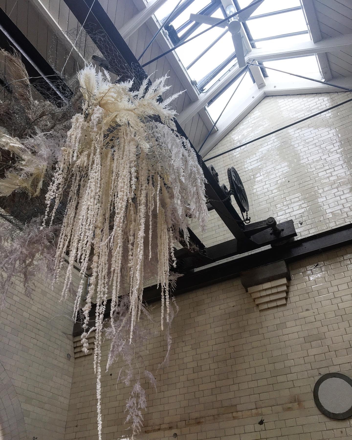 Large suspended dried floral cloud in industrial setting with high ceilings