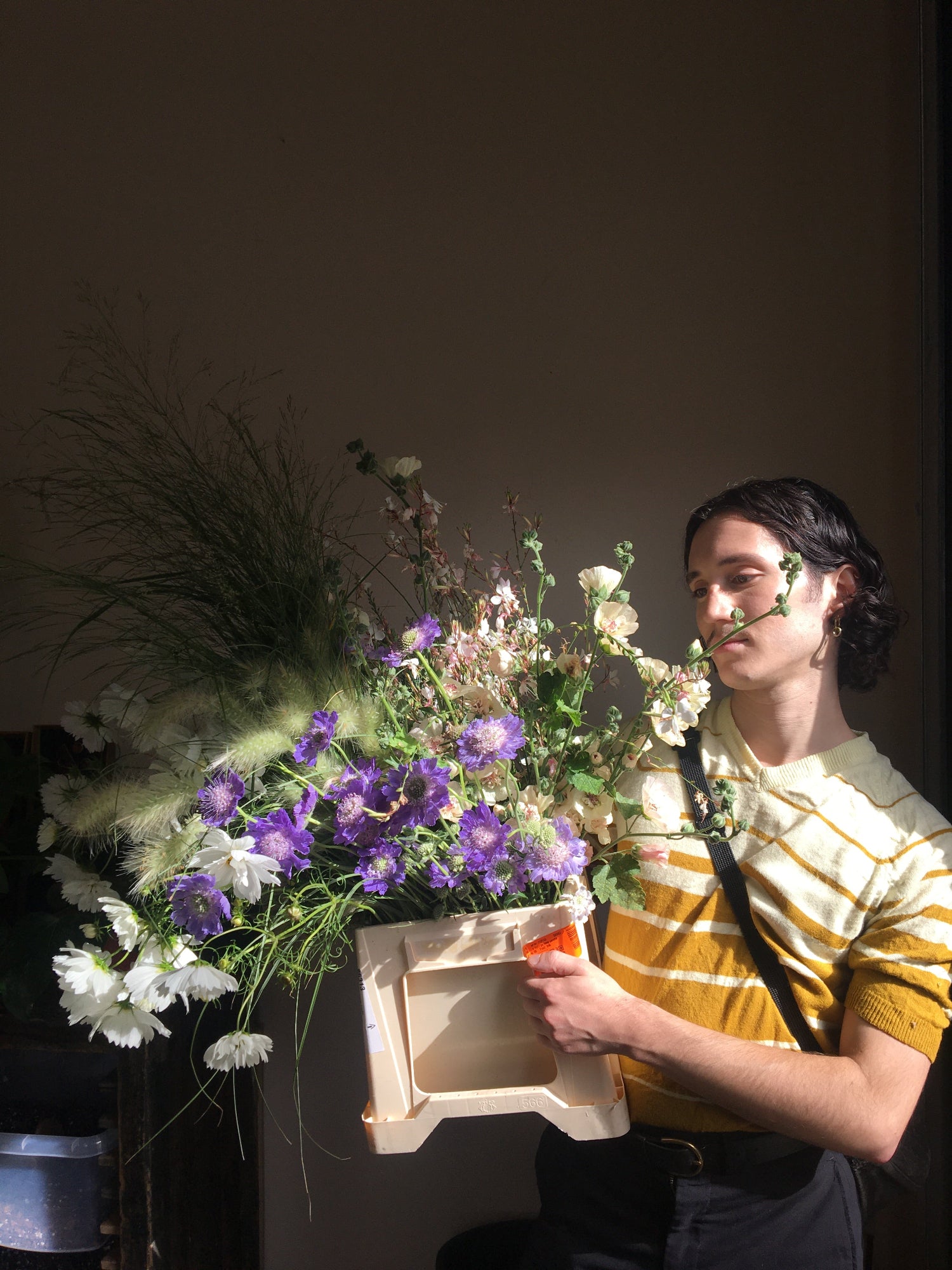 Florist with bucket of fresh flowers from local farmer in white and purple