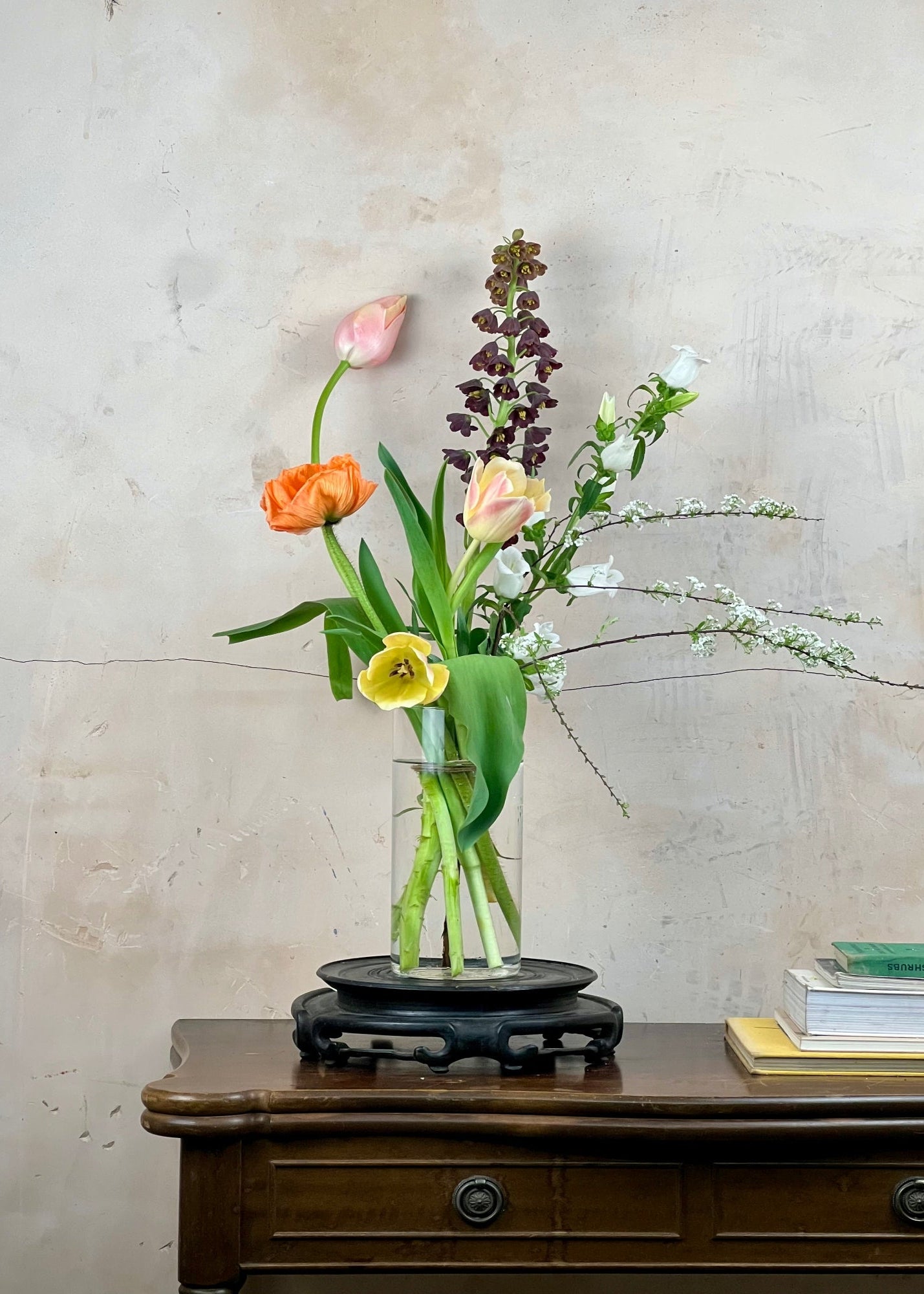 Floral arrangement in a glass vase on a wooden table with a neutral background