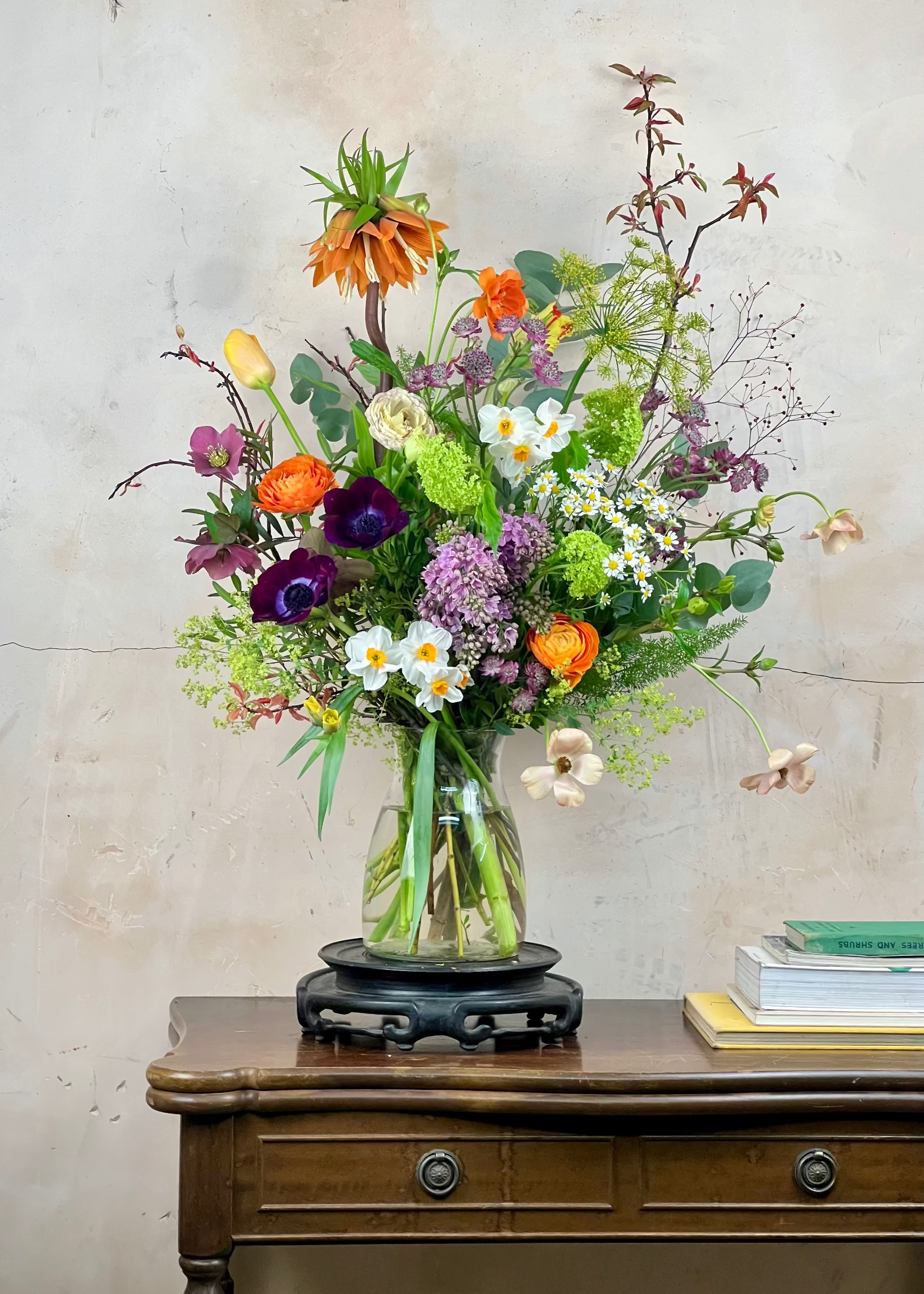 Bouquet of flowers in a glass vase on a wooden table with a light-colored wall background
