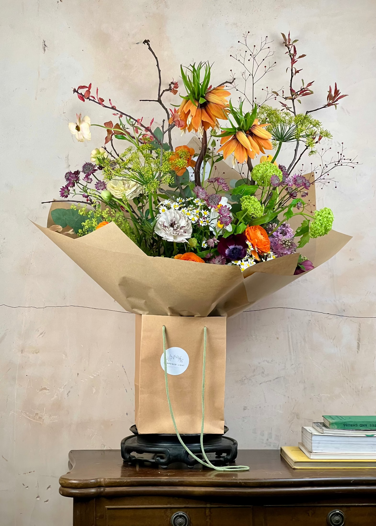 Bouquet of flowers in brown paper packaging on a wooden surface with a neutral background