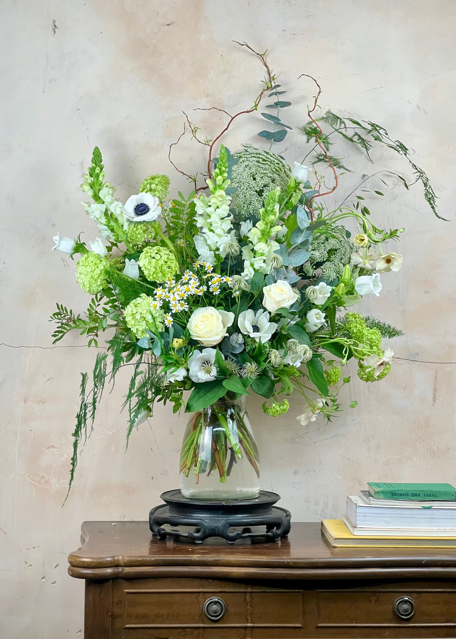 Floral arrangement in a glass vase on a wooden table with a neutral background