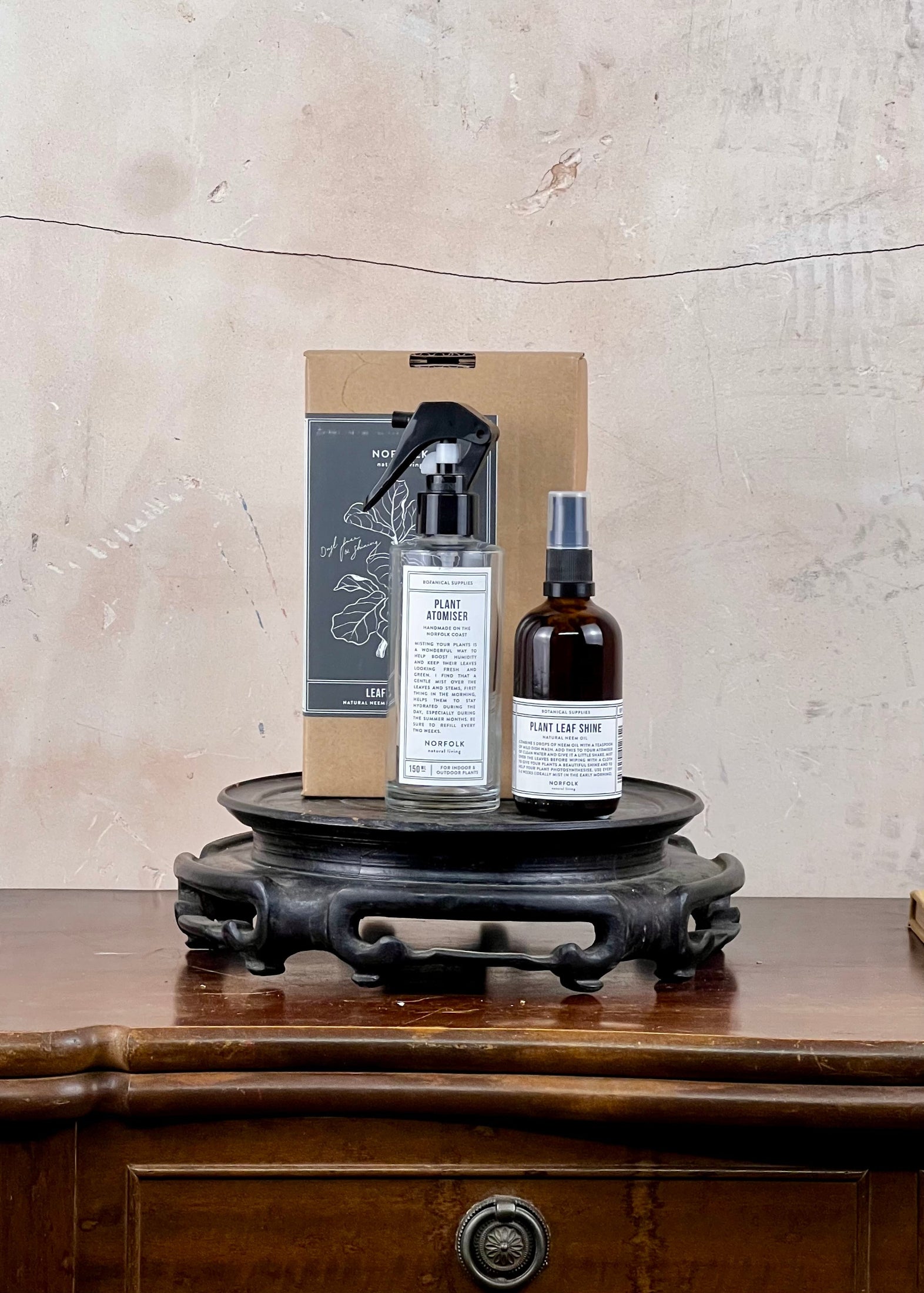 Two spray bottles and a box on a wooden surface with a textured wall background