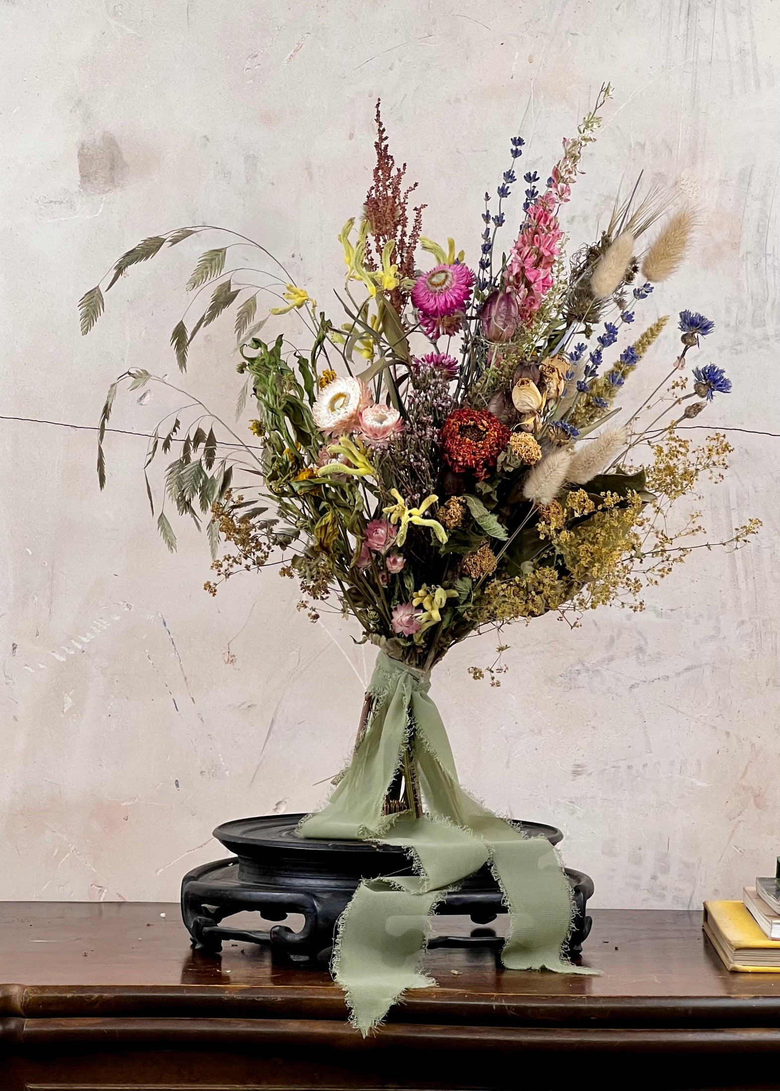 Dried Bridal bouquet of flowers on a wooden table with a textured wall background