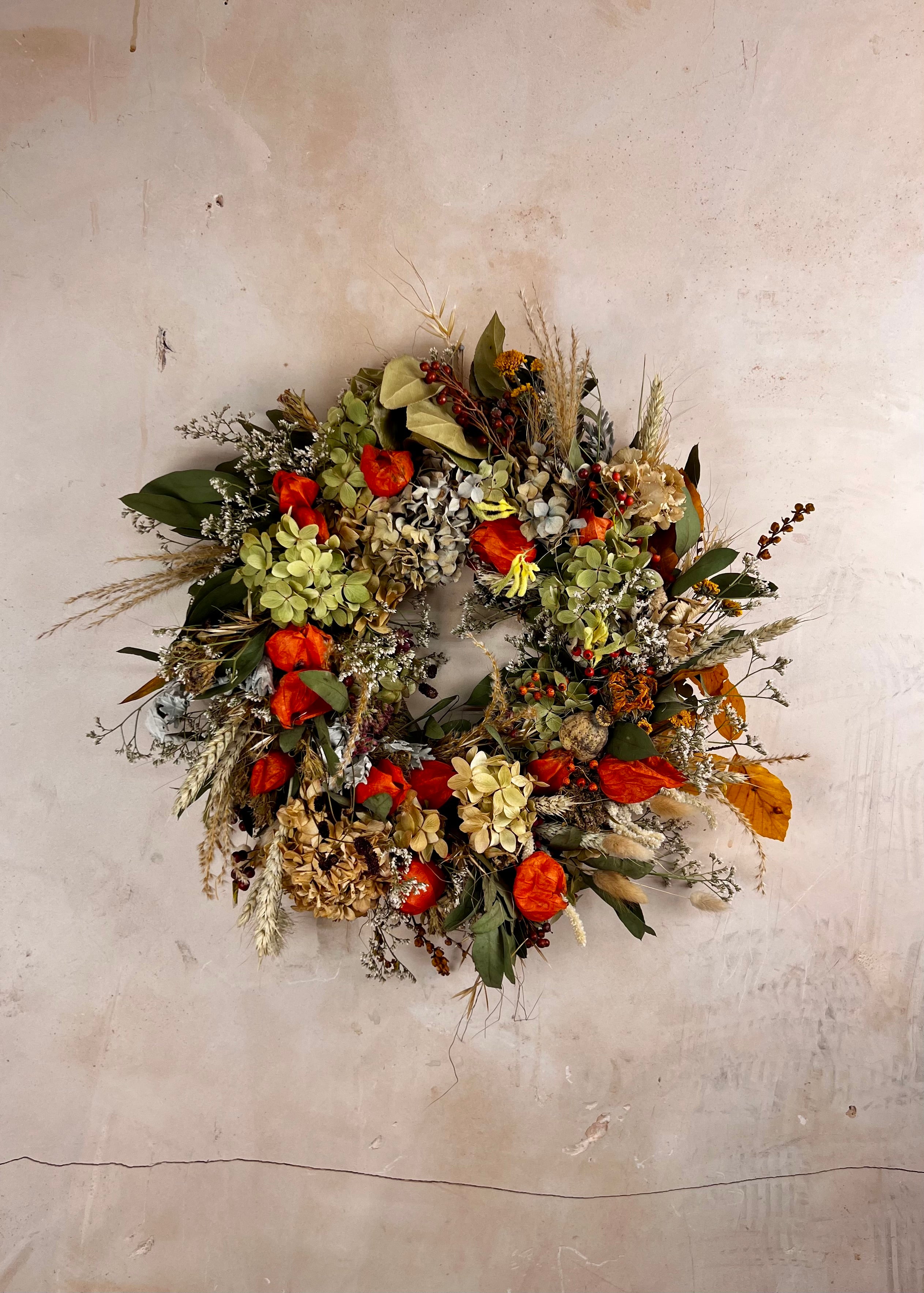 Decorative seasonal dried wreath with autumnal colors on a textured wall