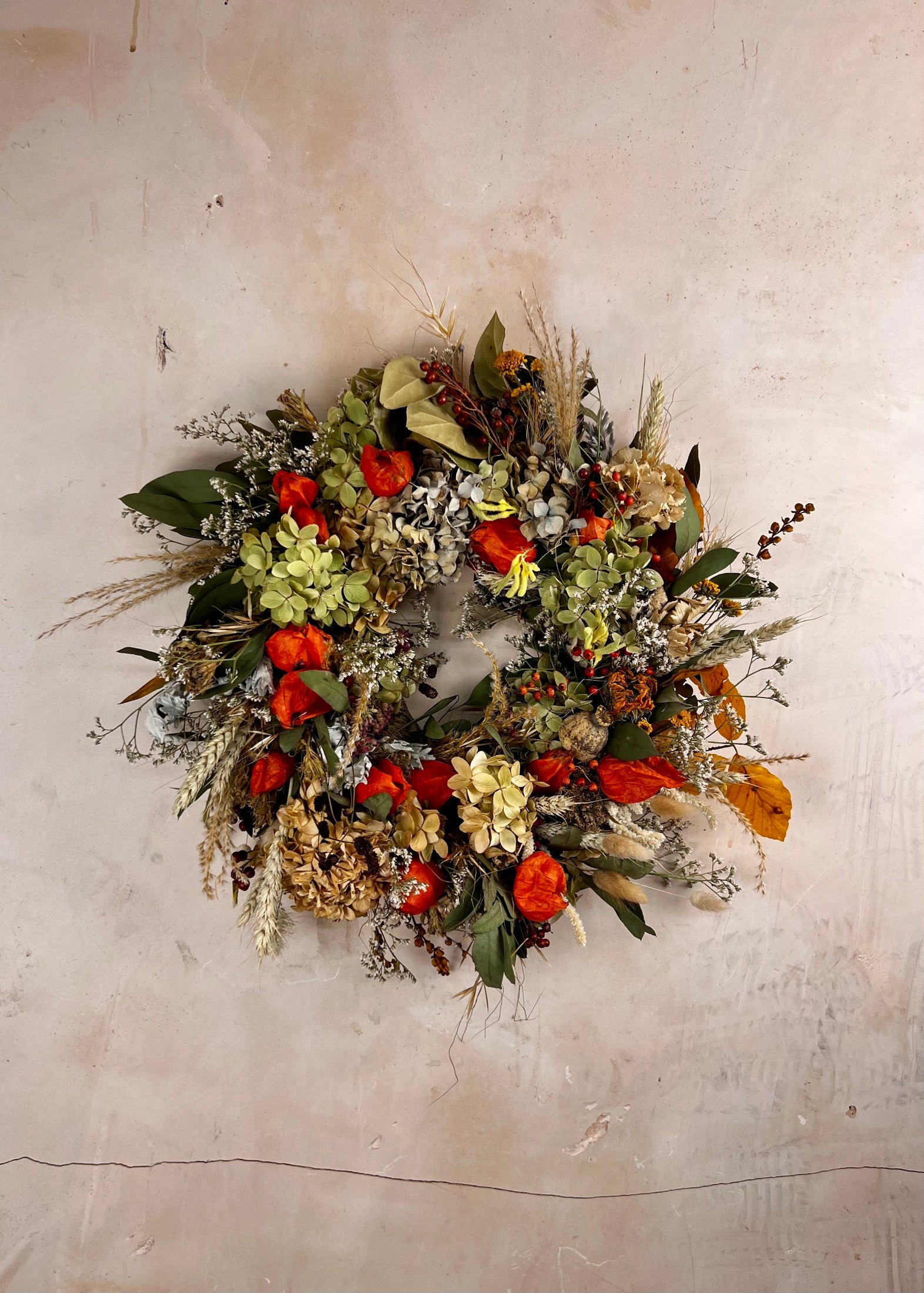 Decorative seasonal dried wreath with autumnal colors on a textured wall
