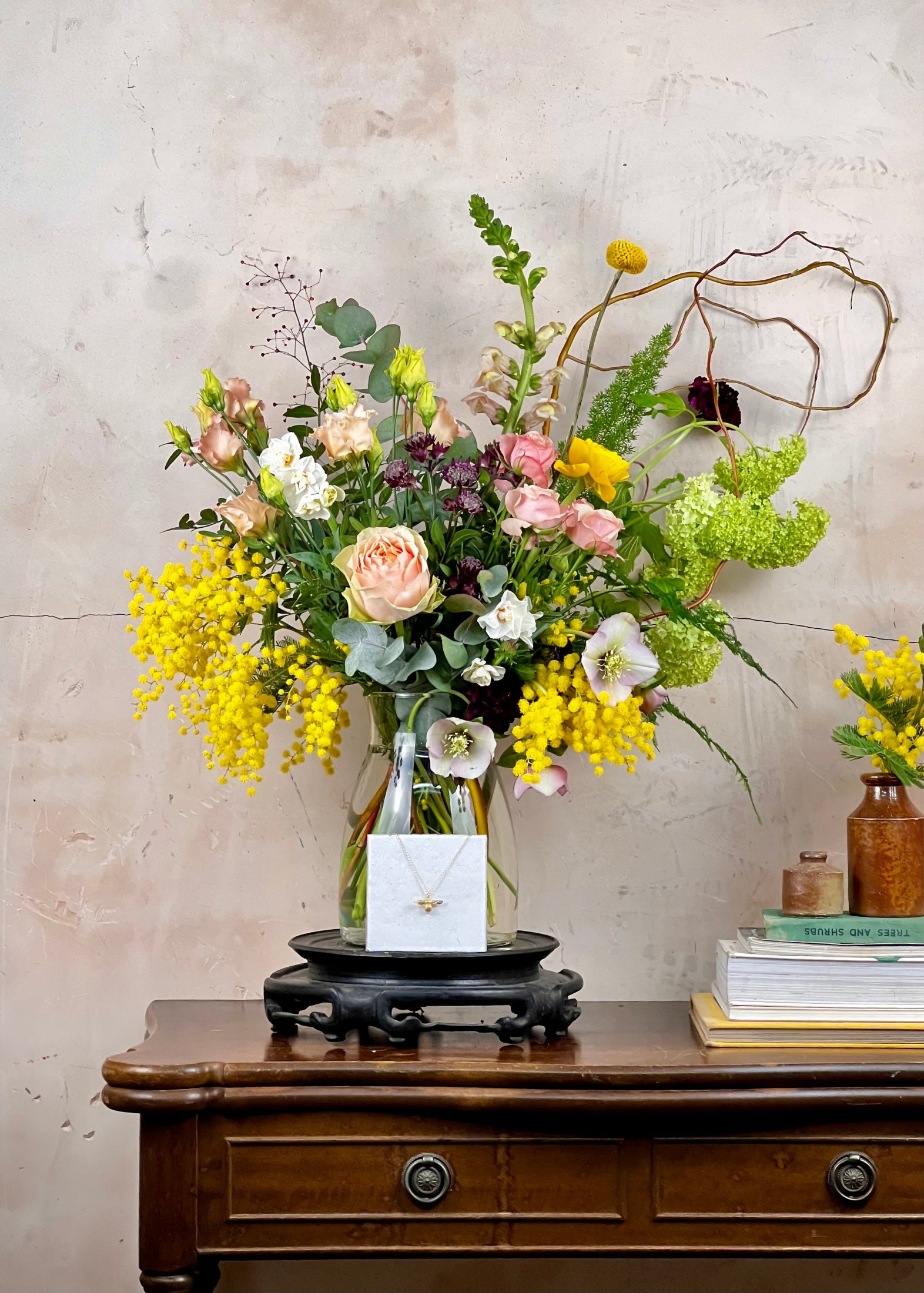 Floral arrangement in a glass vase on a wooden table with a textured wall background