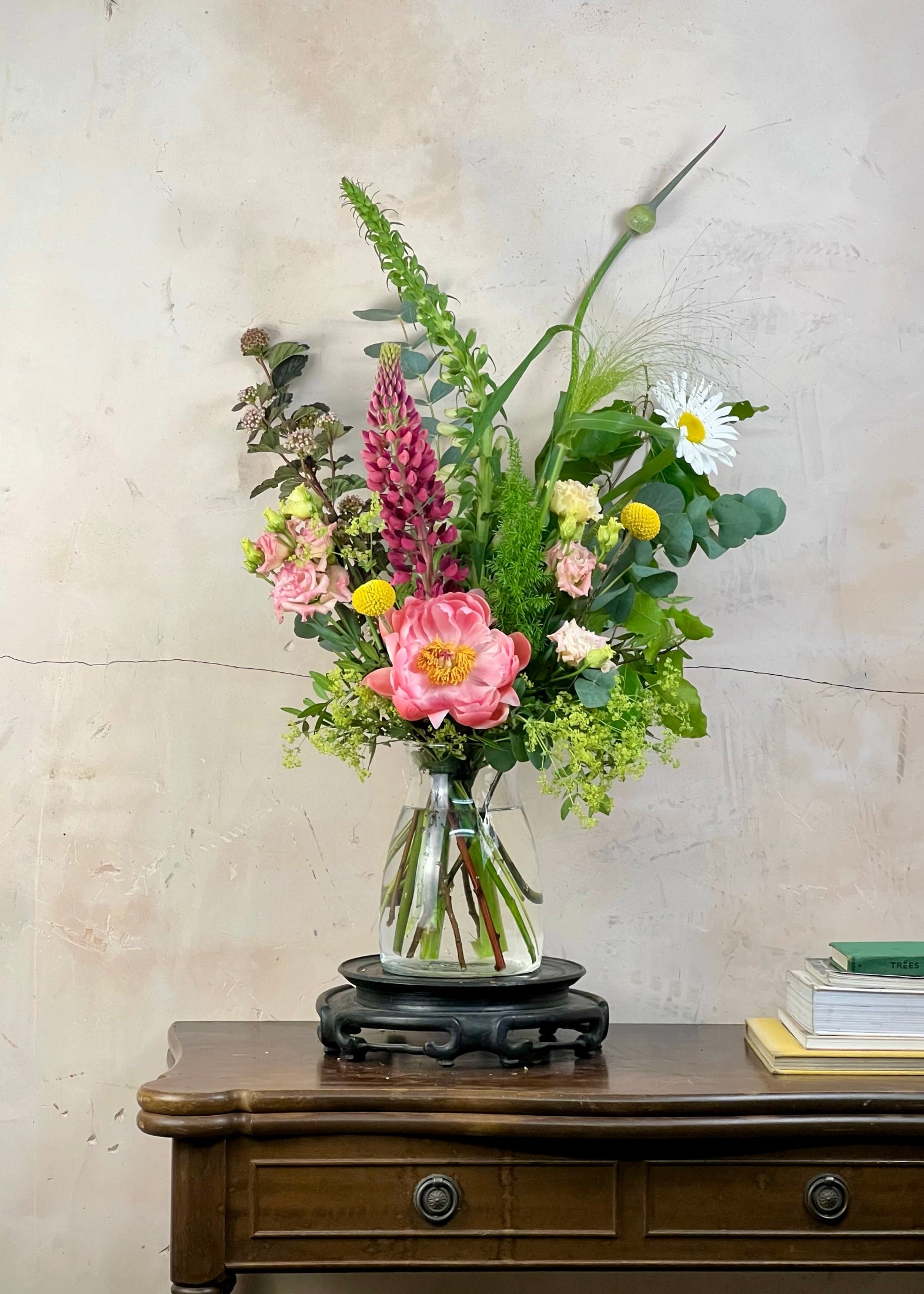 Floral arrangement in a clear vase on a wooden table with a light background