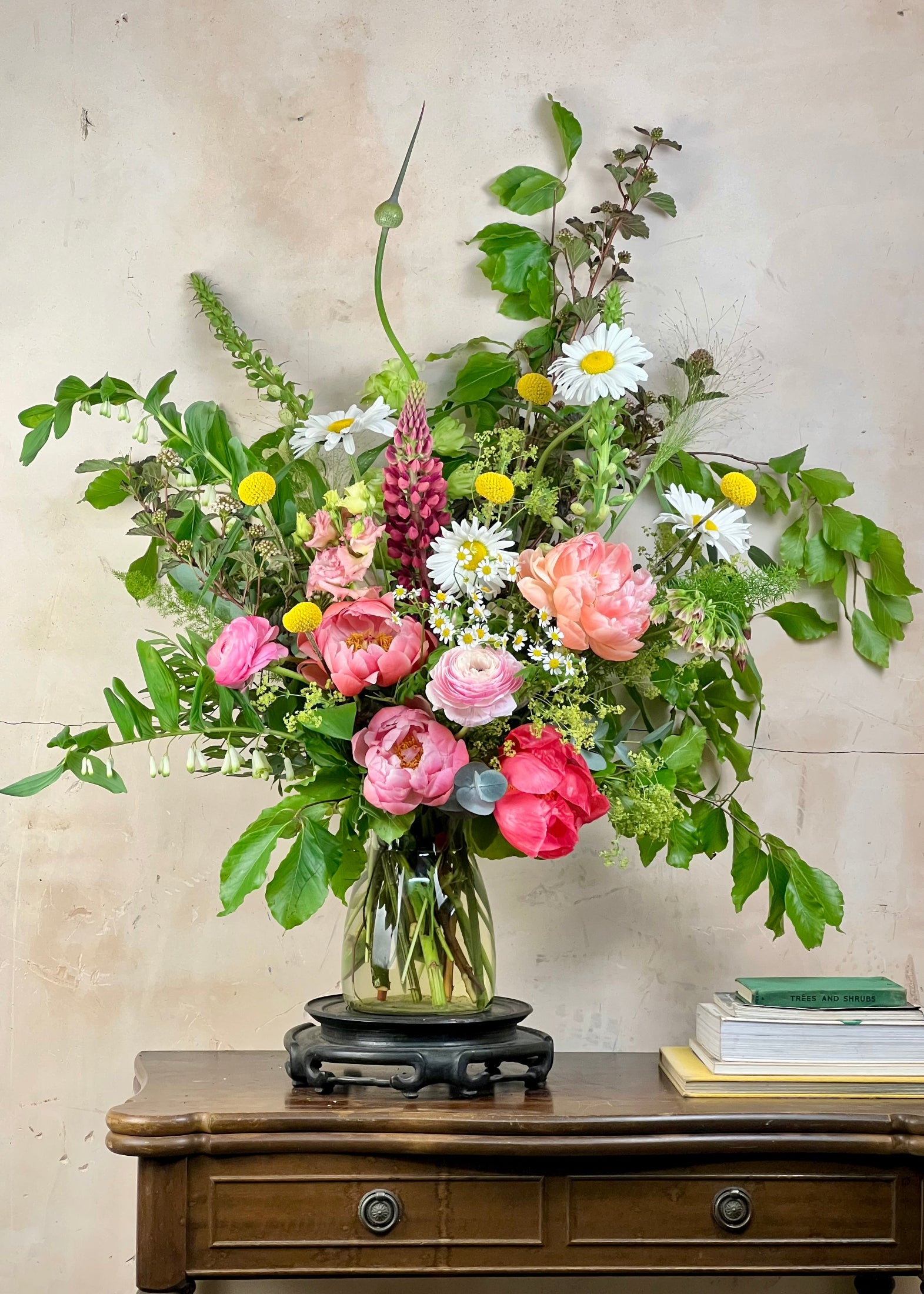 Bouquet of flowers in a glass vase on a wooden table with a neutral background