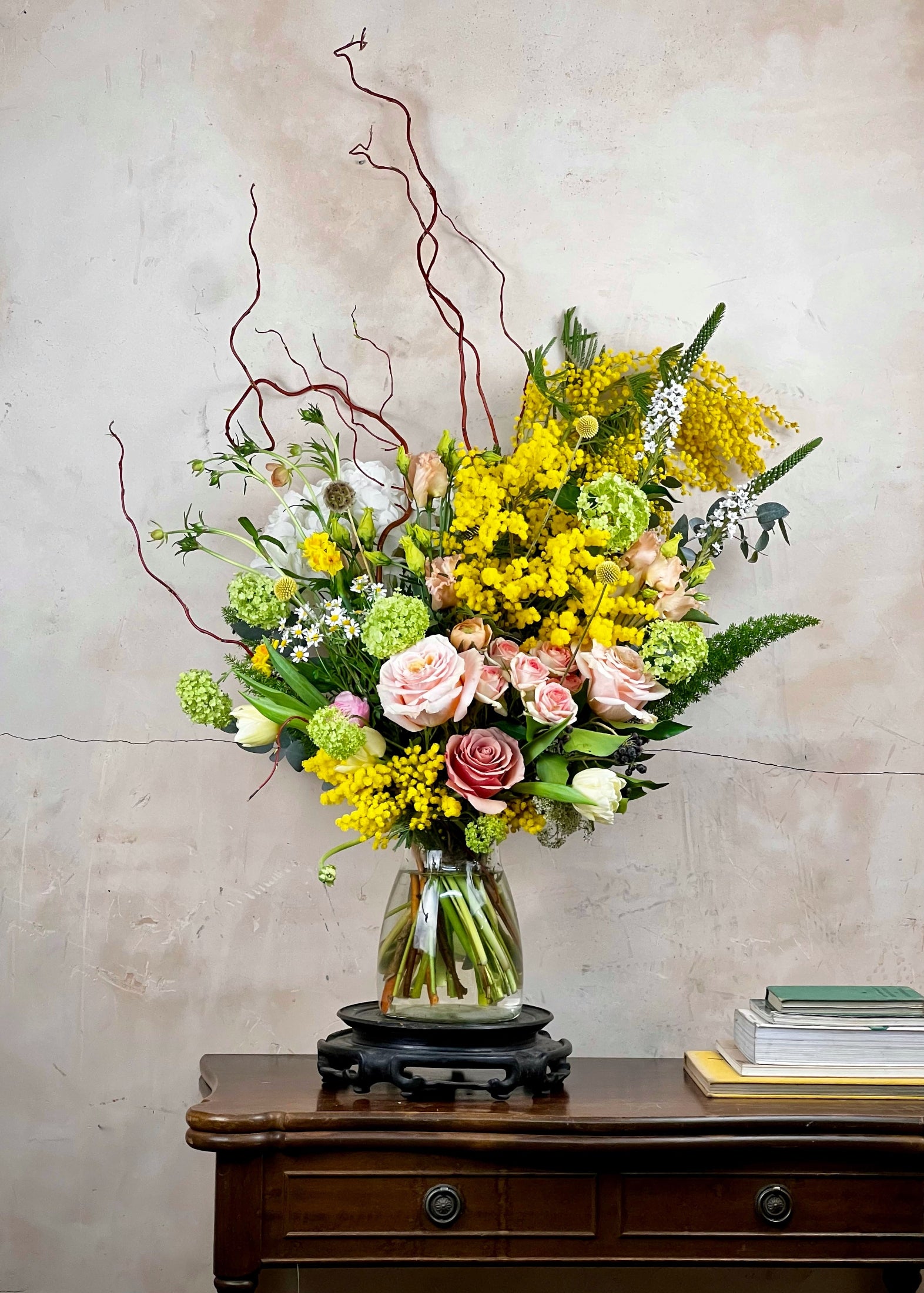 Floral arrangement in a glass vase on a wooden table with a neutral background