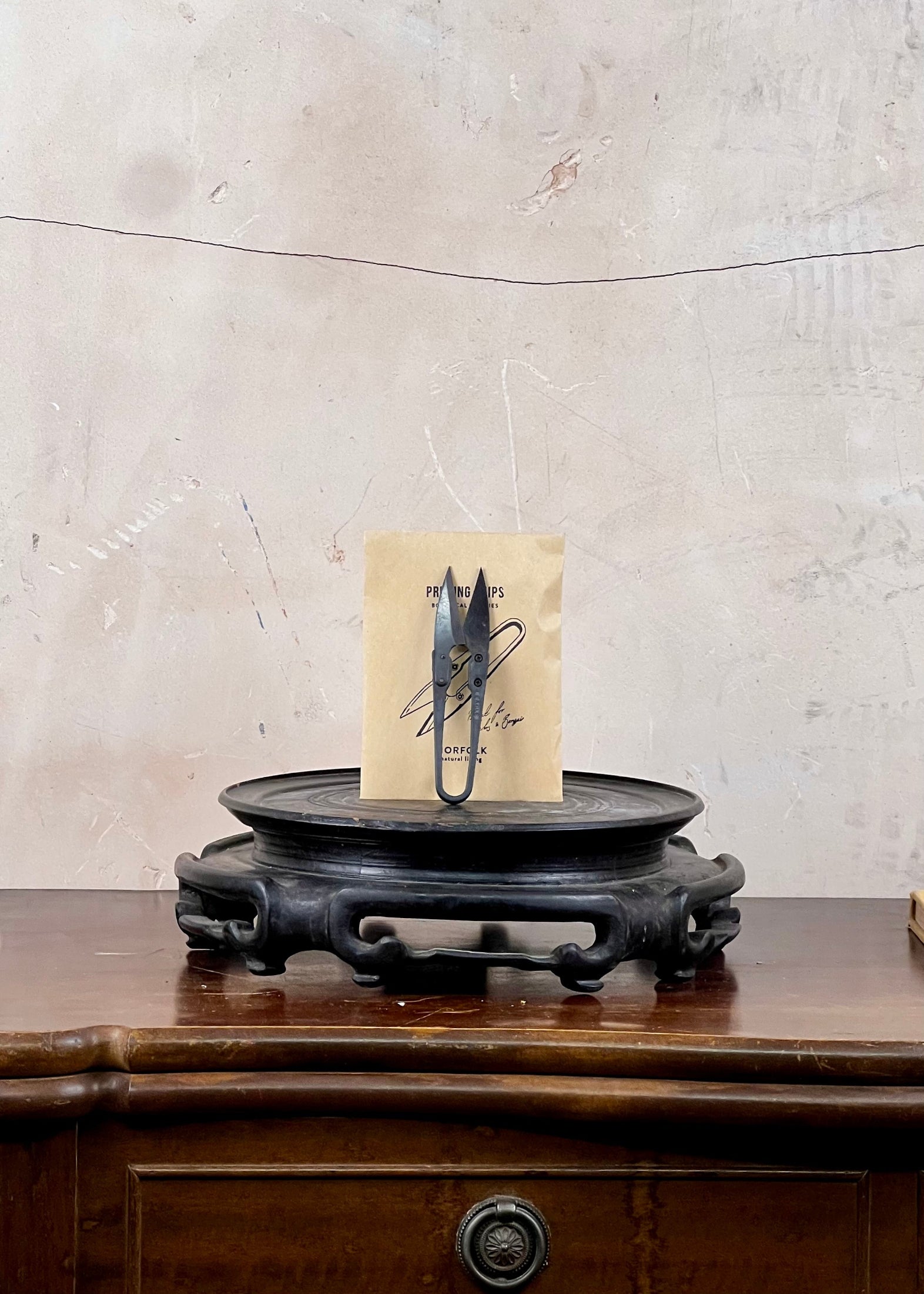 Scissors on a wooden stand with a textured wall background