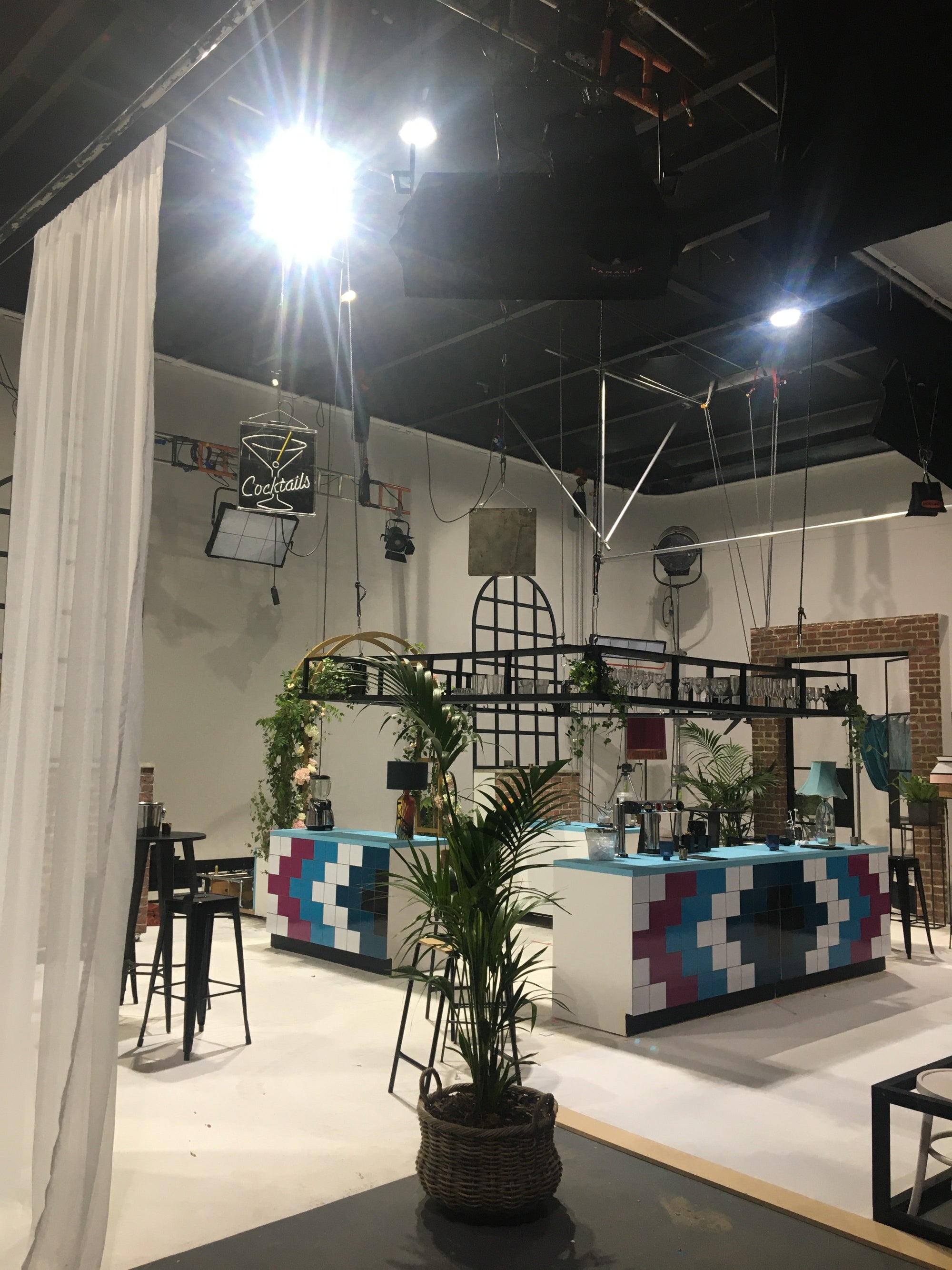 Stage set for tv show married at first sight showing the set for the bar and a floral arch and decorative plants