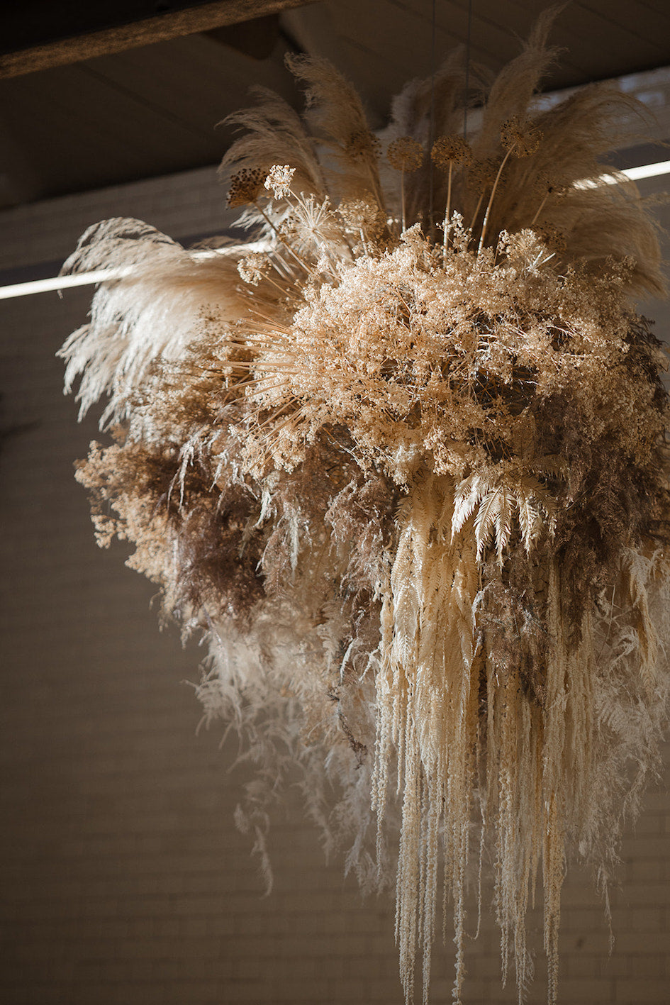 Dried pampas grass  and dried flowers hanging from a ceiling to form a cloud shape