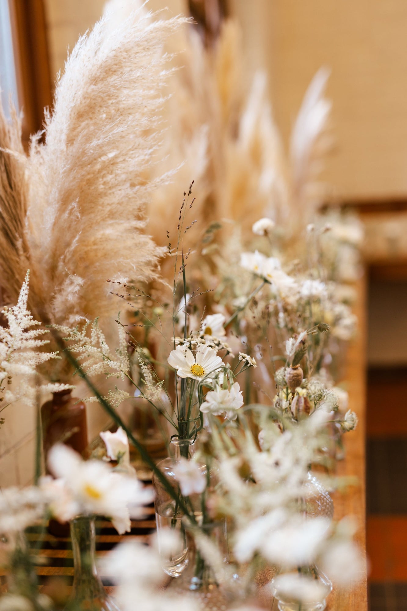 Decorative arrangement with pampas grass and white flowers in a blurred indoor setting