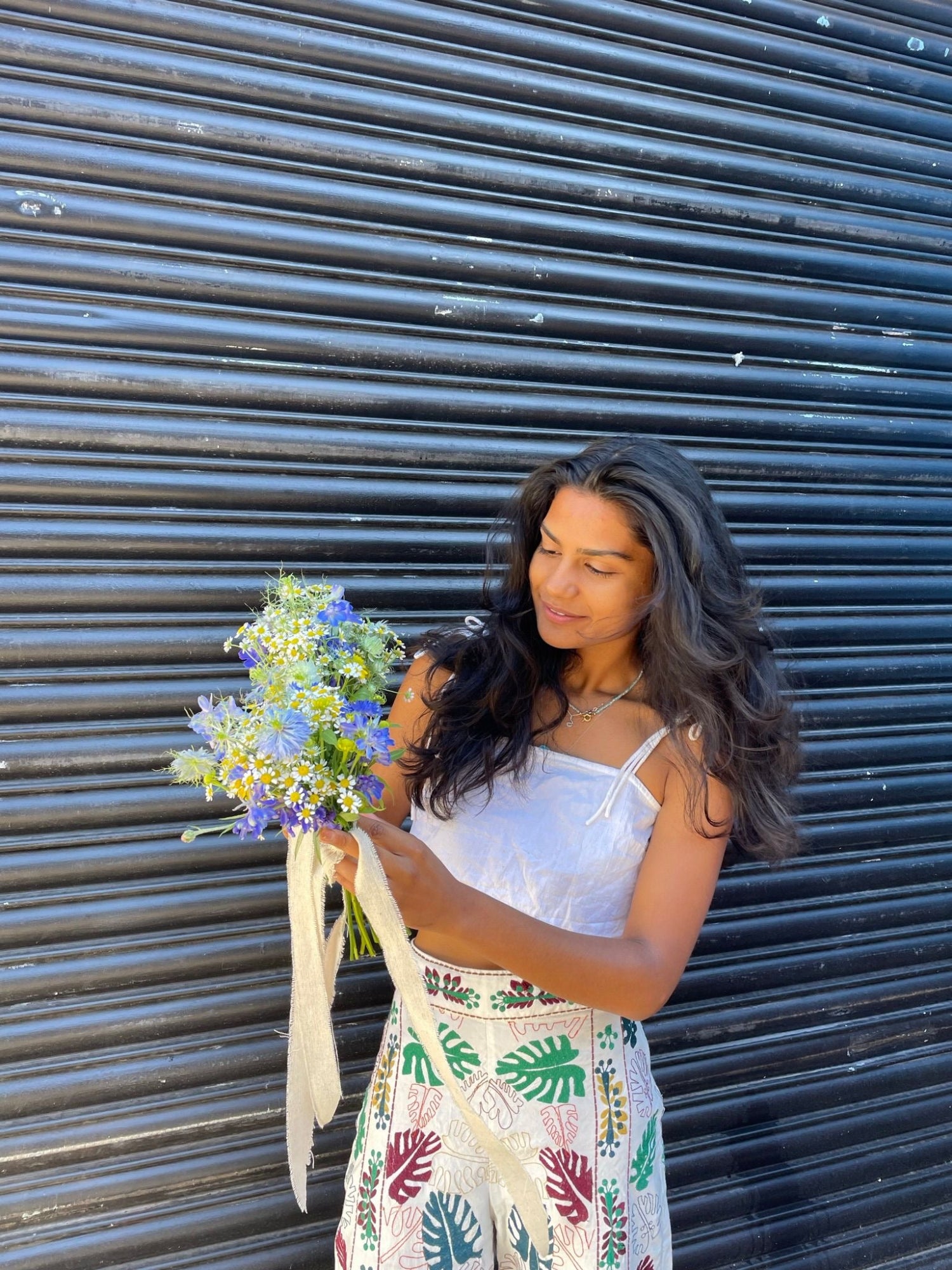 Woman holding flowers against a corrugated metal background