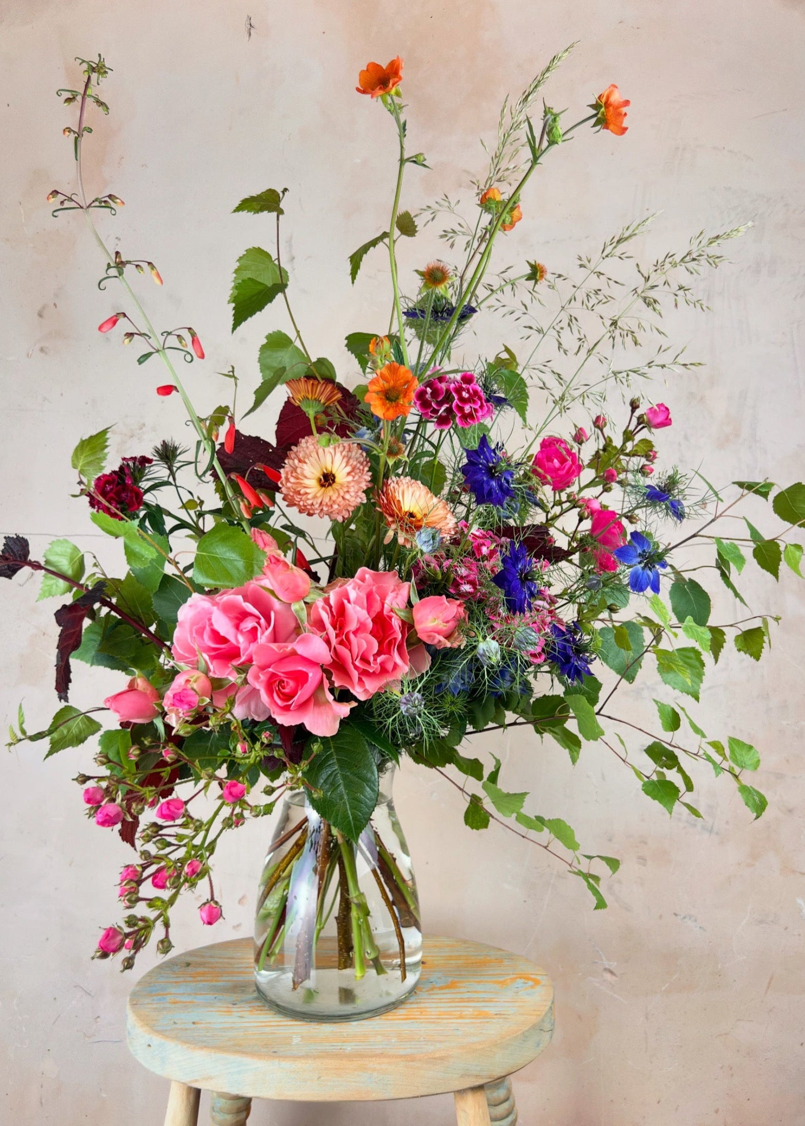 Vase of colorful flowers on a small table against a light background