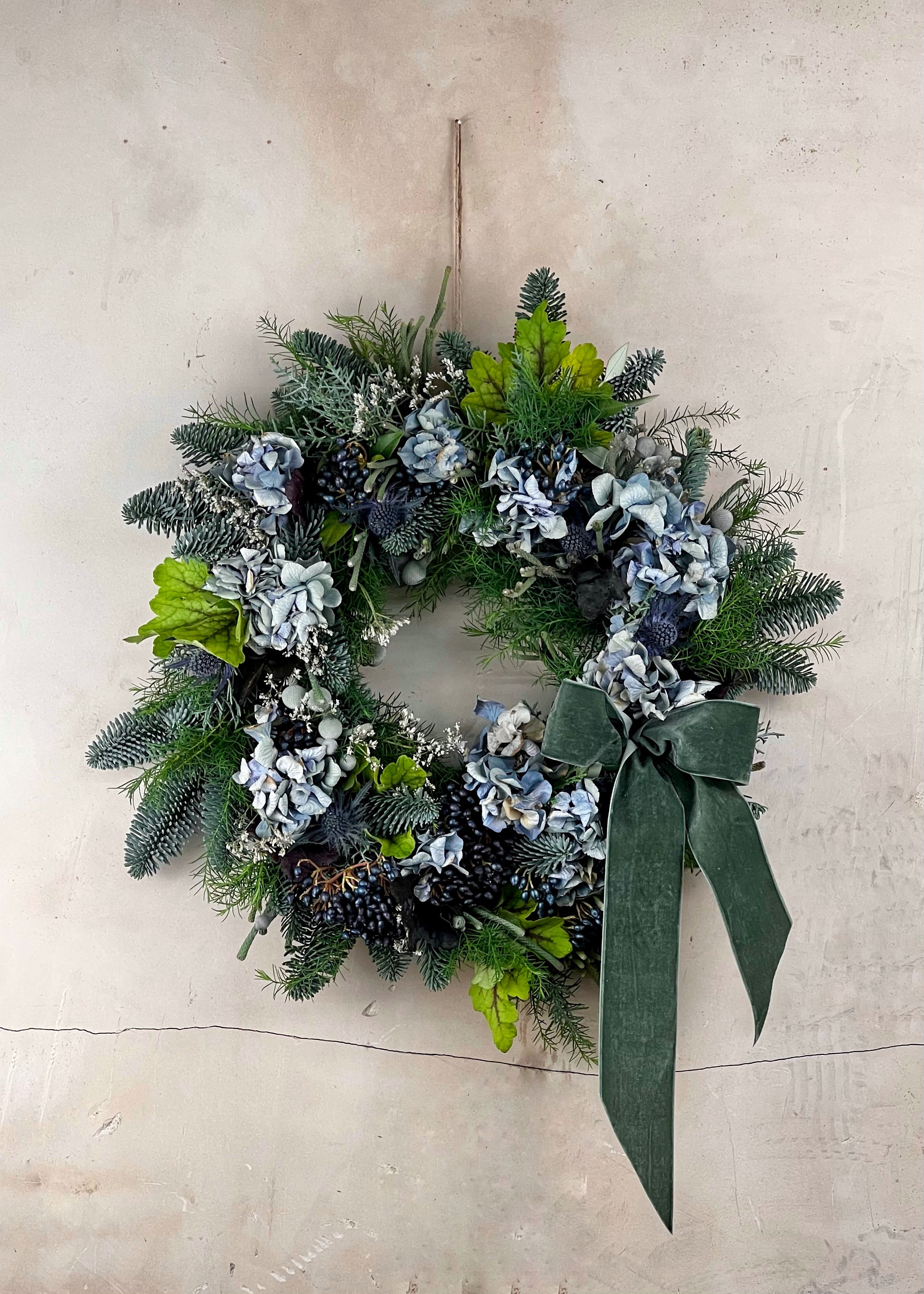 Decorative wreath with greenery and flowers on a beige background