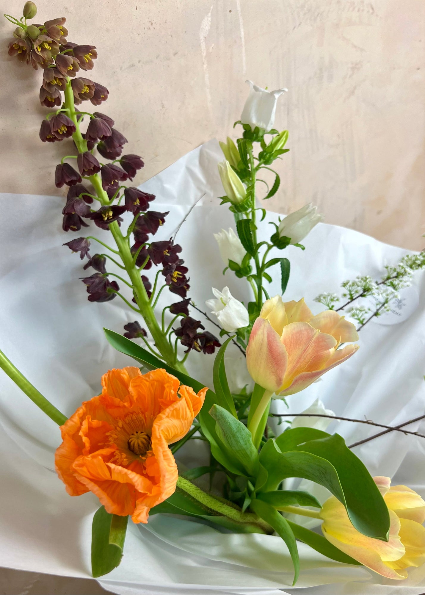 Bouquet of flowers including orange, yellow, and purple flowers on a white surface.