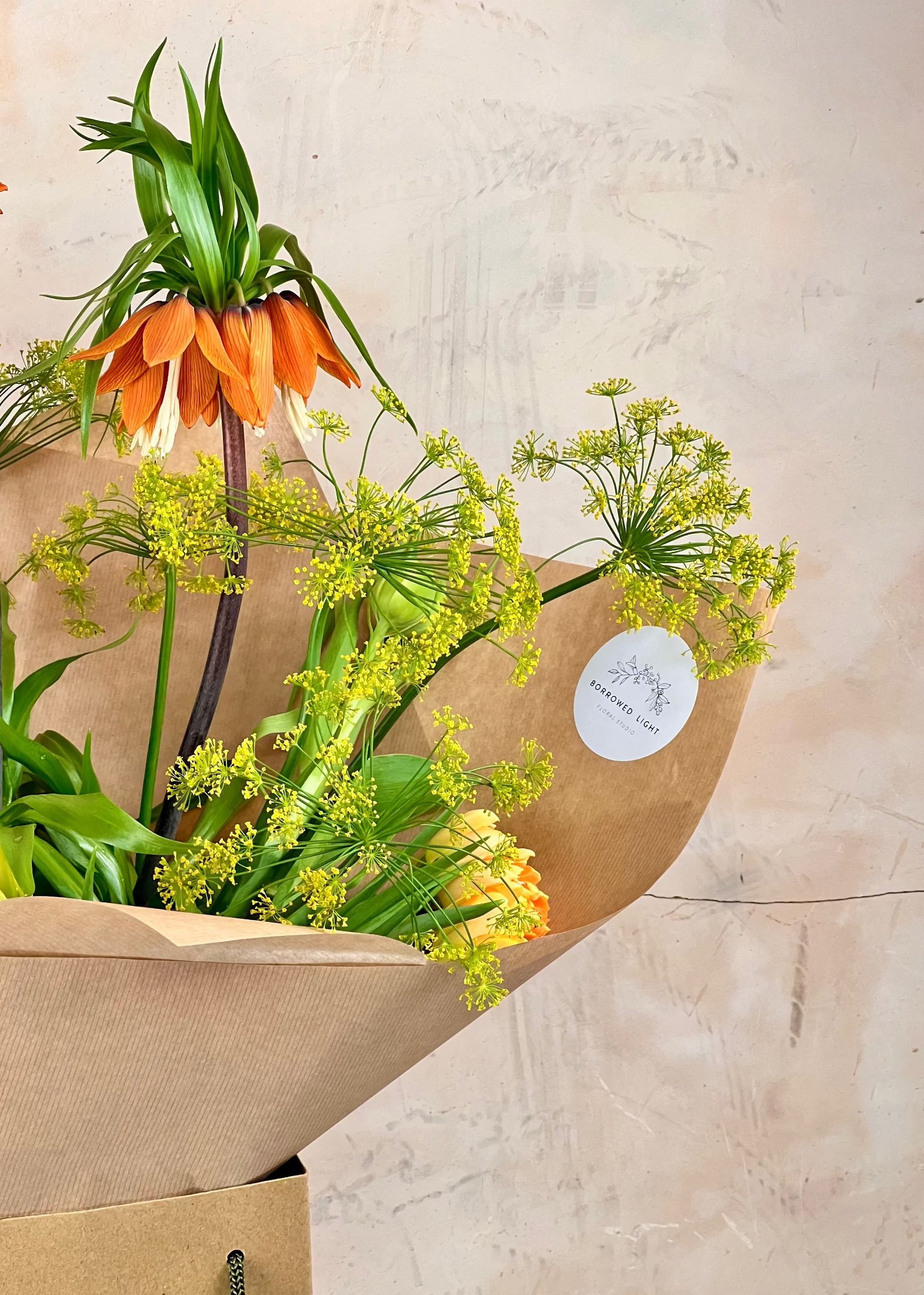 Bouquet of flowers wrapped in brown paper with a beige background