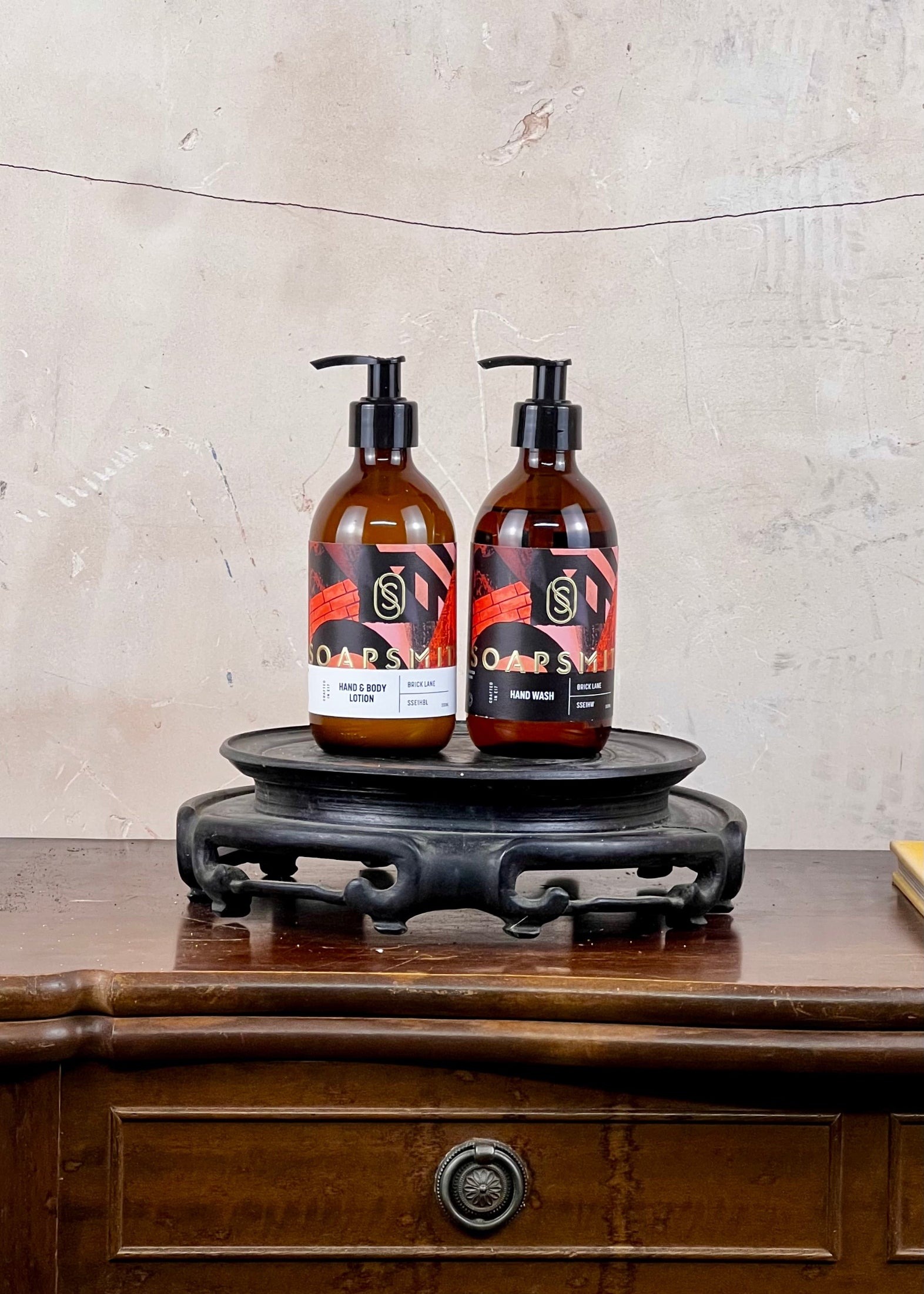 Two brown bottles with pump dispensers on a wooden surface against a textured wall.