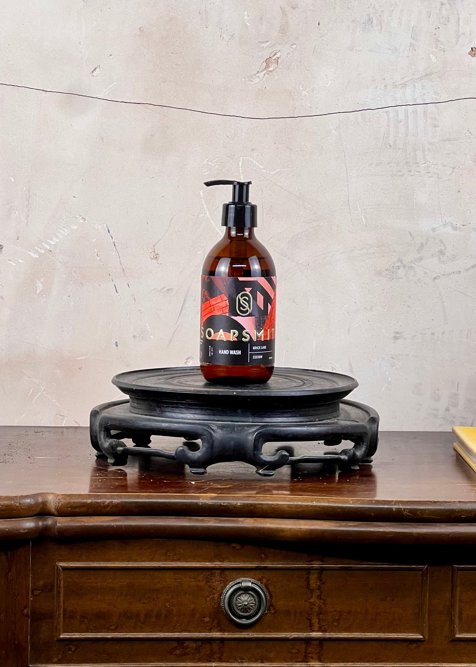 Hand wash in a brown glass bottle with a colorful label on a wooden surface and stone wall background
