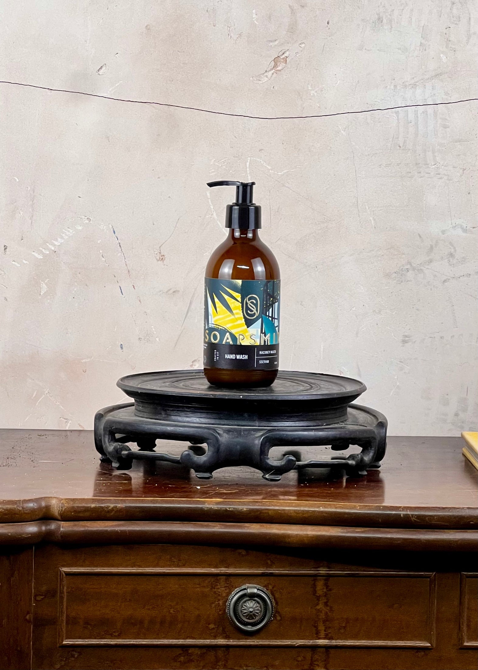Hand wash in a brown glass bottle with a colorful label on a wooden surface and stone wall background