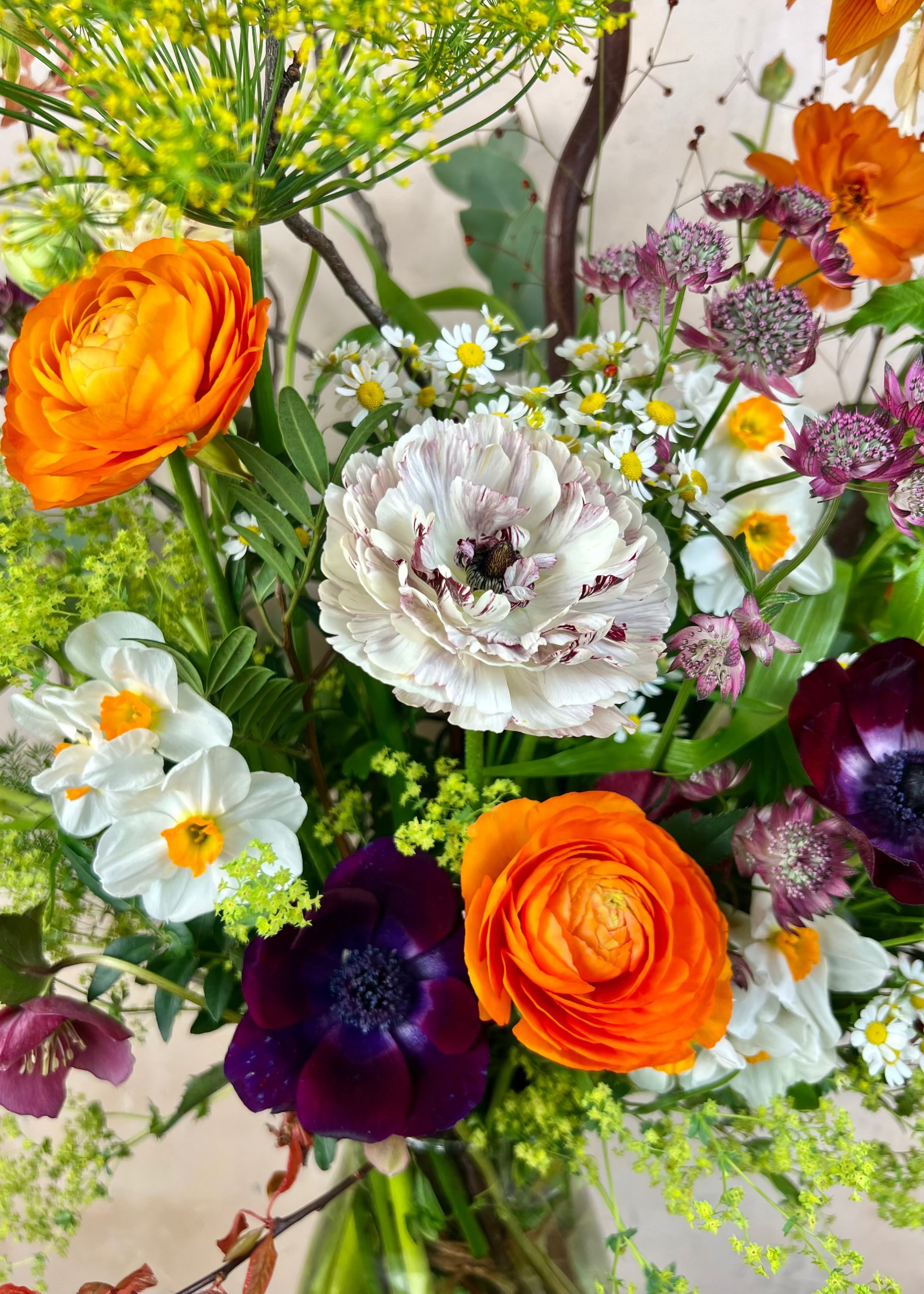 Bouquet of colorful flowers including orange, white, and purple in a clear vase.