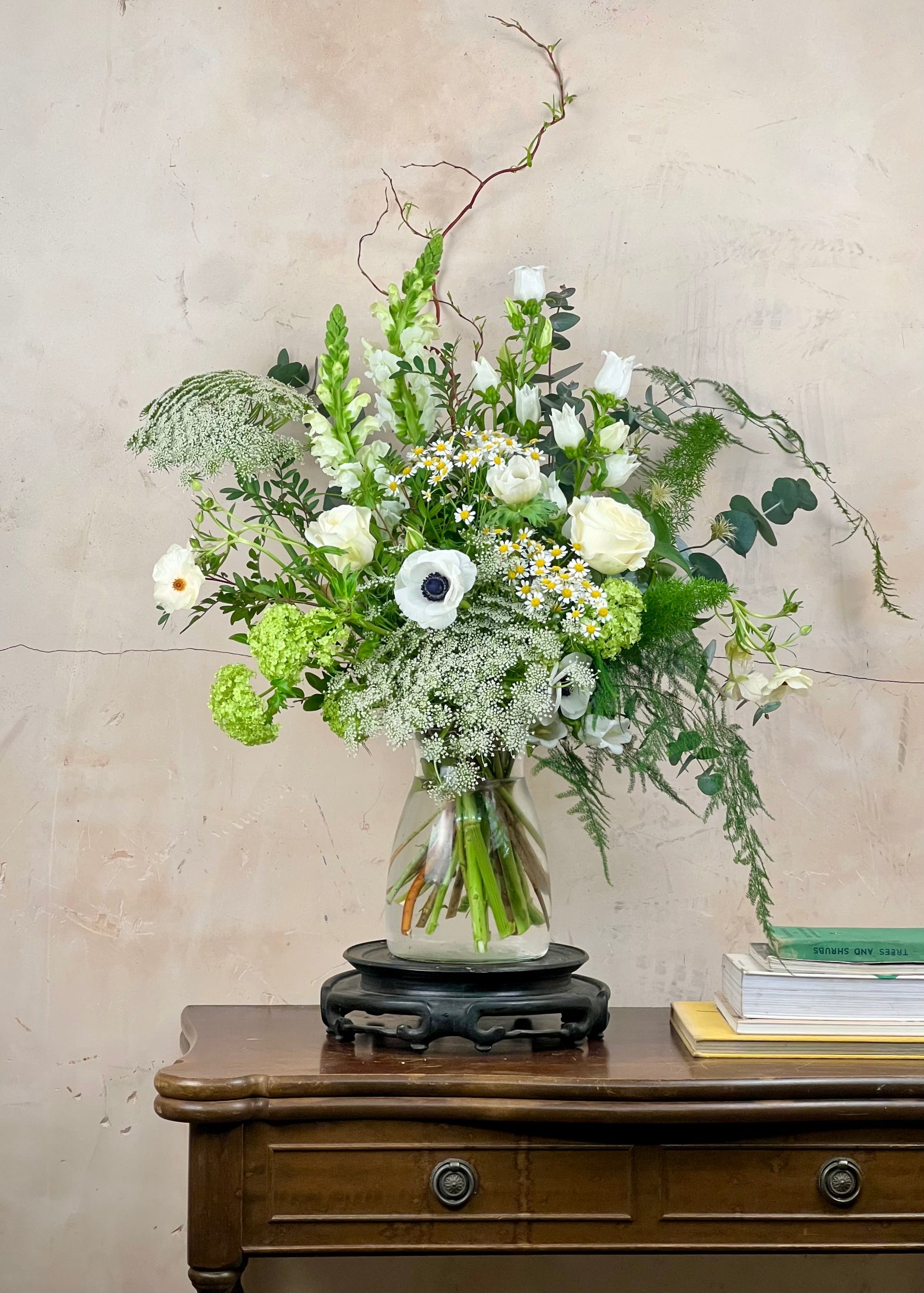 Floral arrangement in a glass vase on a wooden table with a neutral background