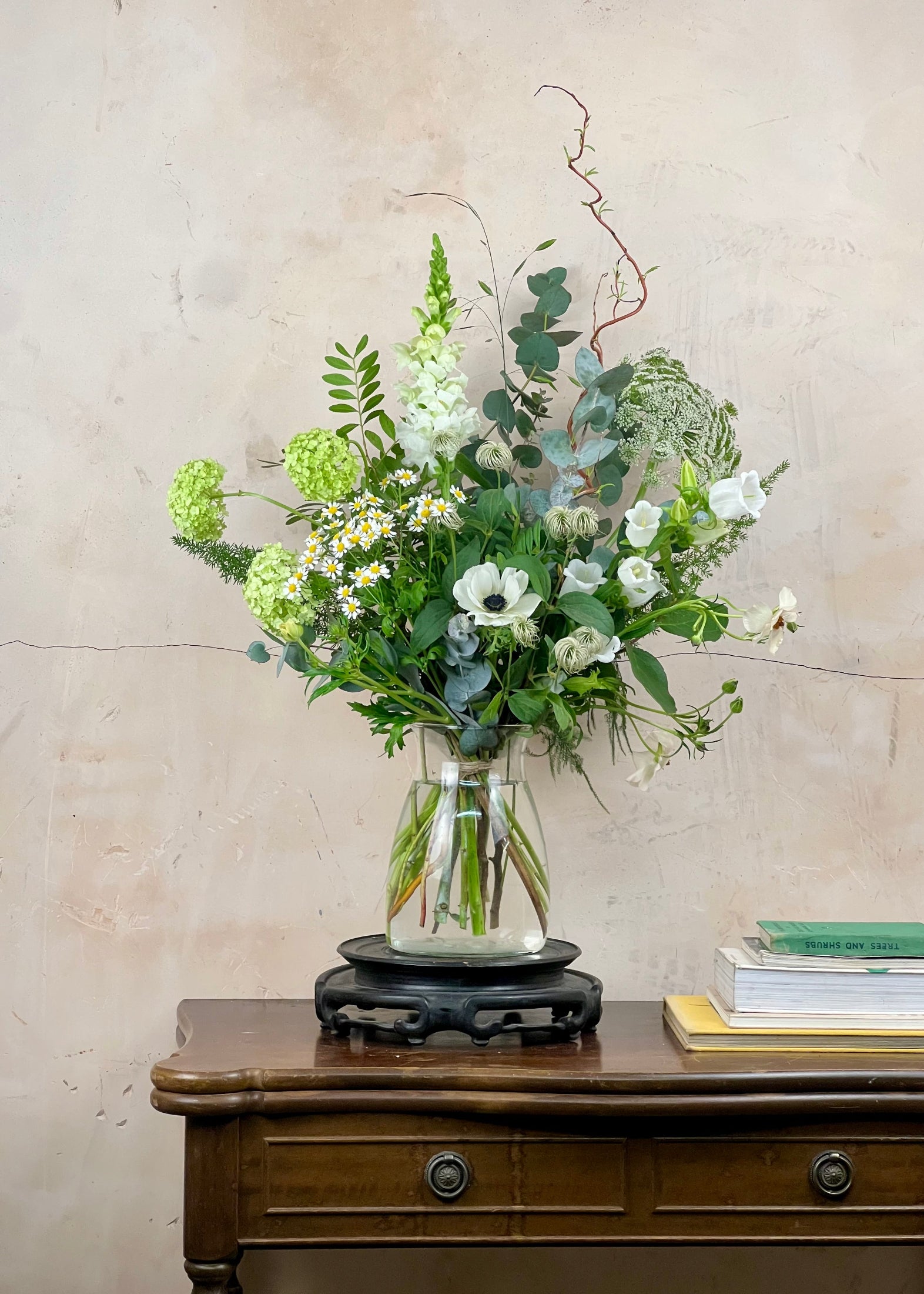 Bouquet of flowers in a glass vase on a wooden table with a neutral background
