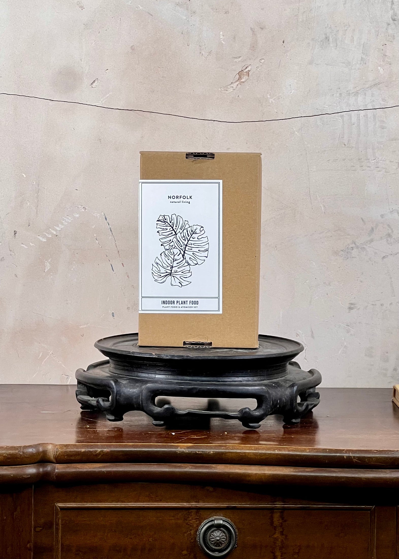 Kraft paper box with a label on a wooden surface against a textured wall.