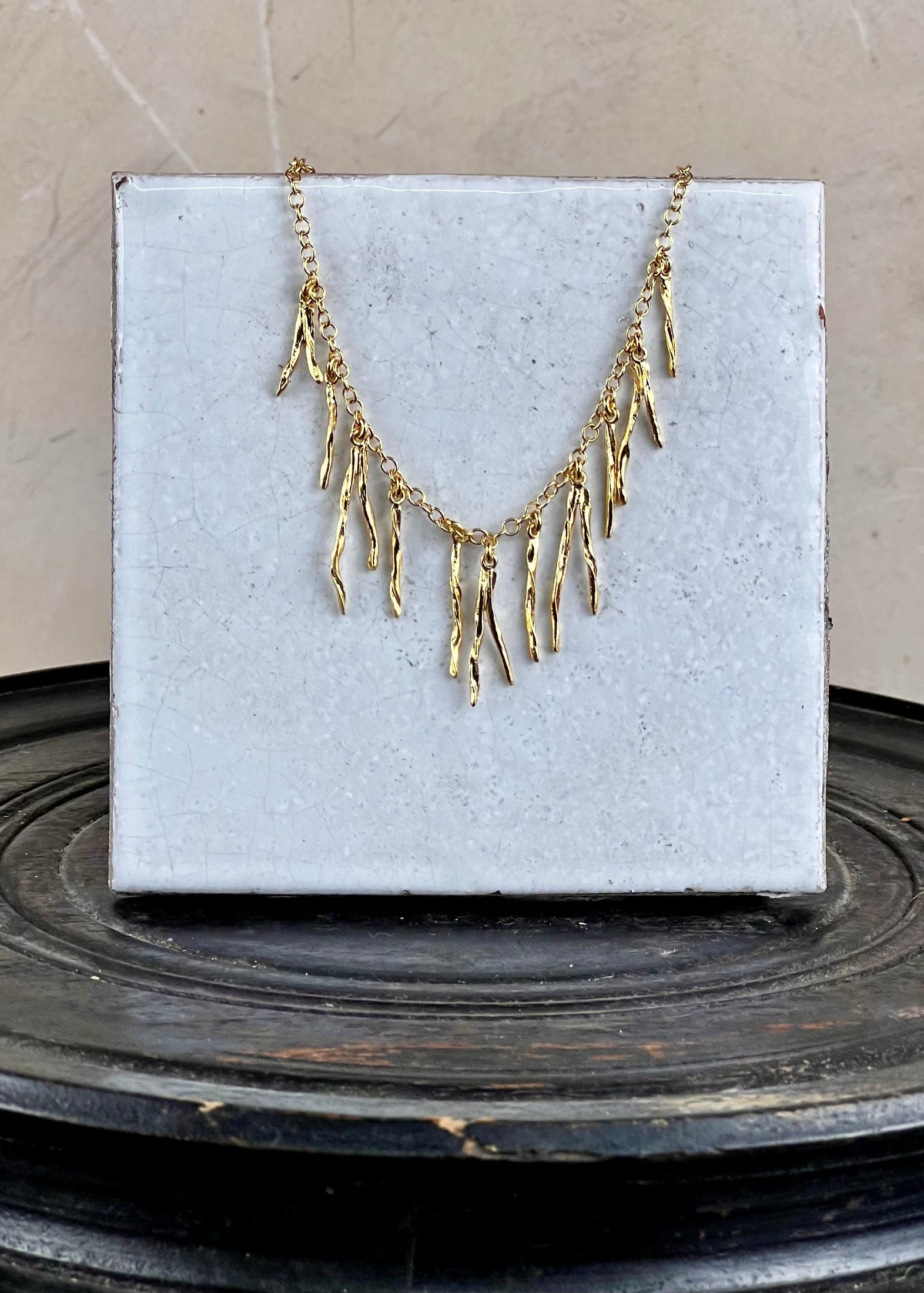 Gold necklace on a white box with a neutral background