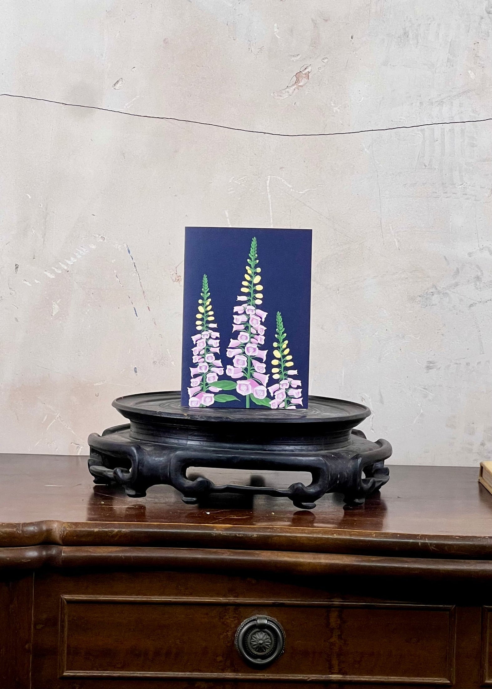 Card with floral design on a wooden stand against a textured wall.