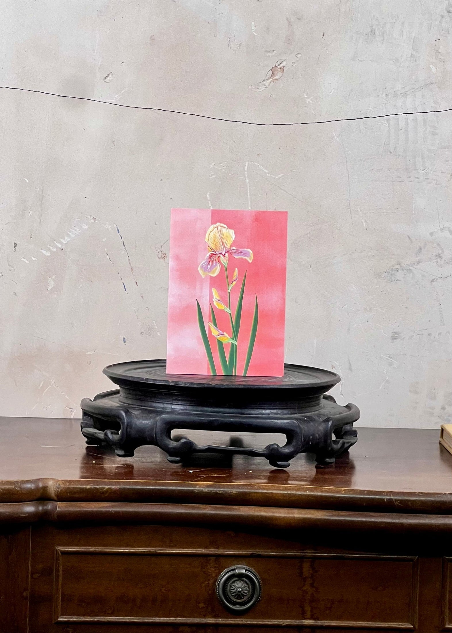 Card with floral design on a wooden stand against a textured wall.