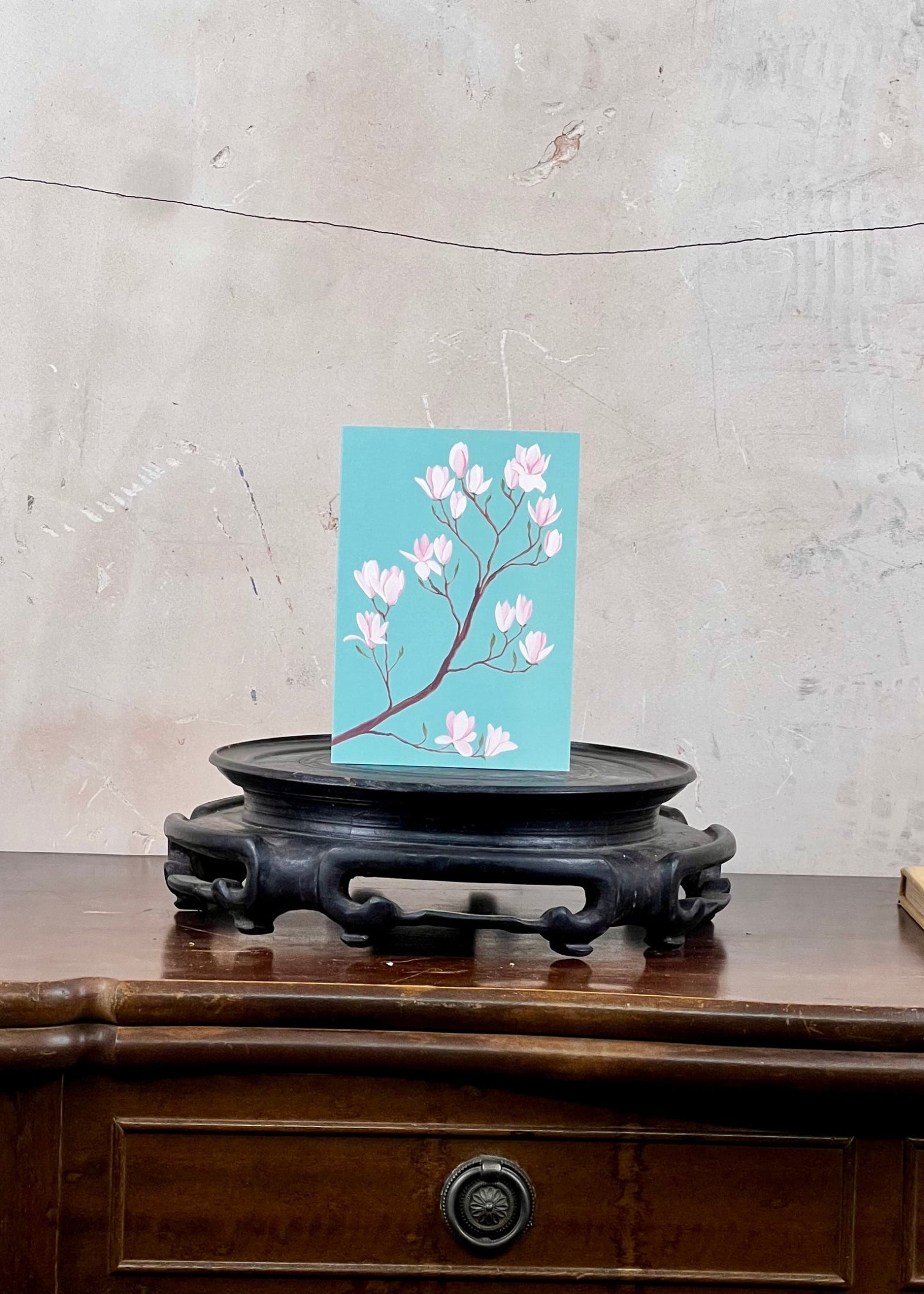 Card with floral design on a stand against a textured wall