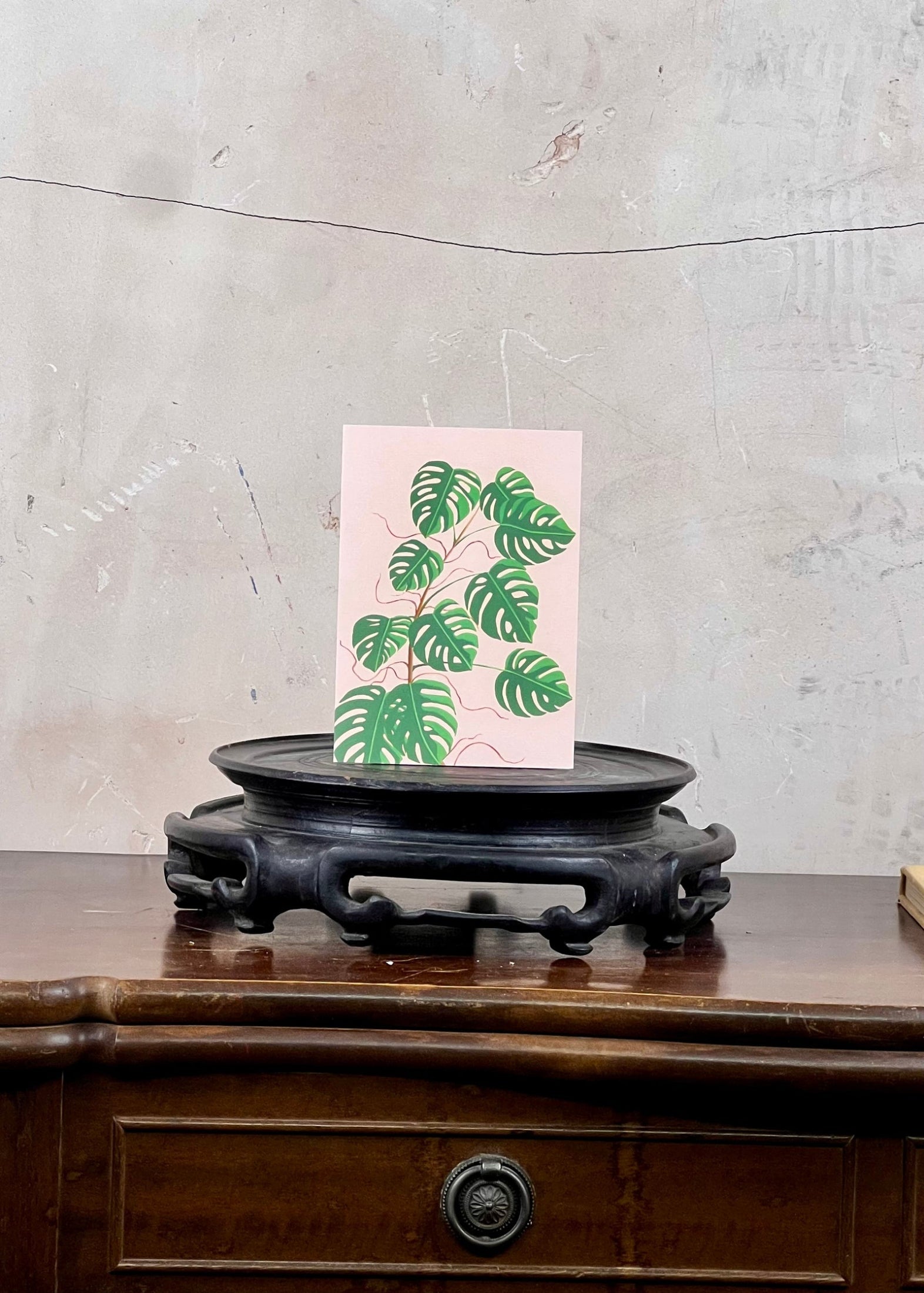 Card with green leaf design on a wooden stand against a textured wall.
