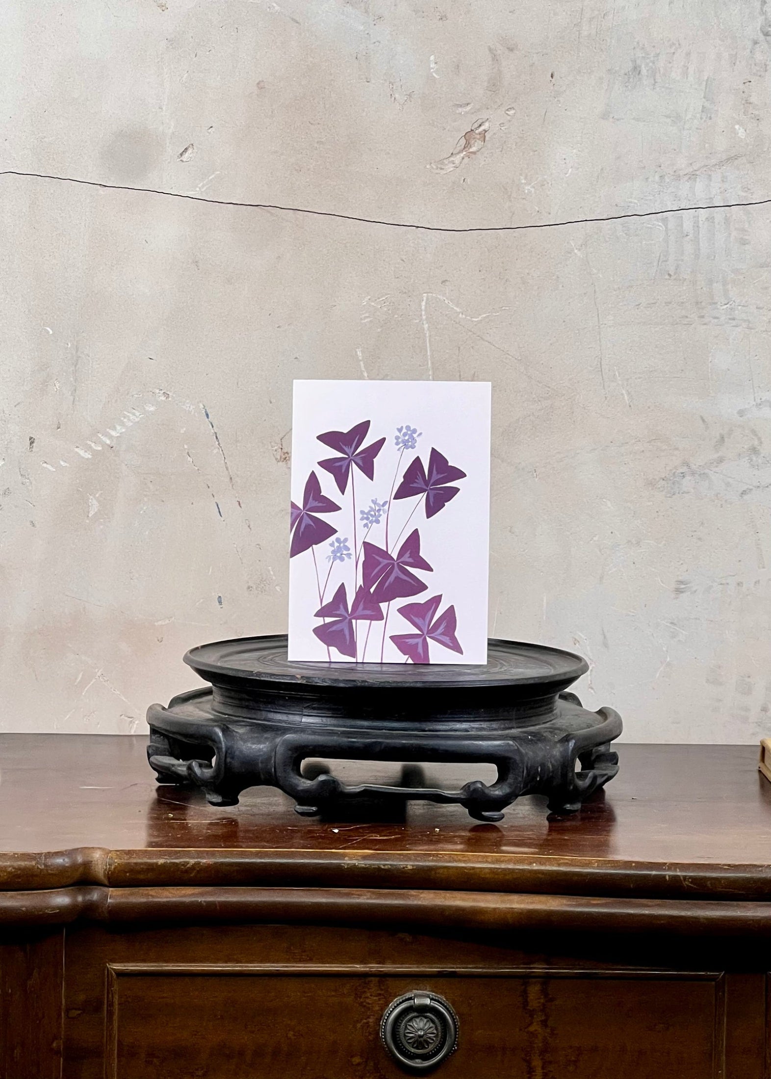 Card with purple butterfly design on a wooden stand against a textured wall.