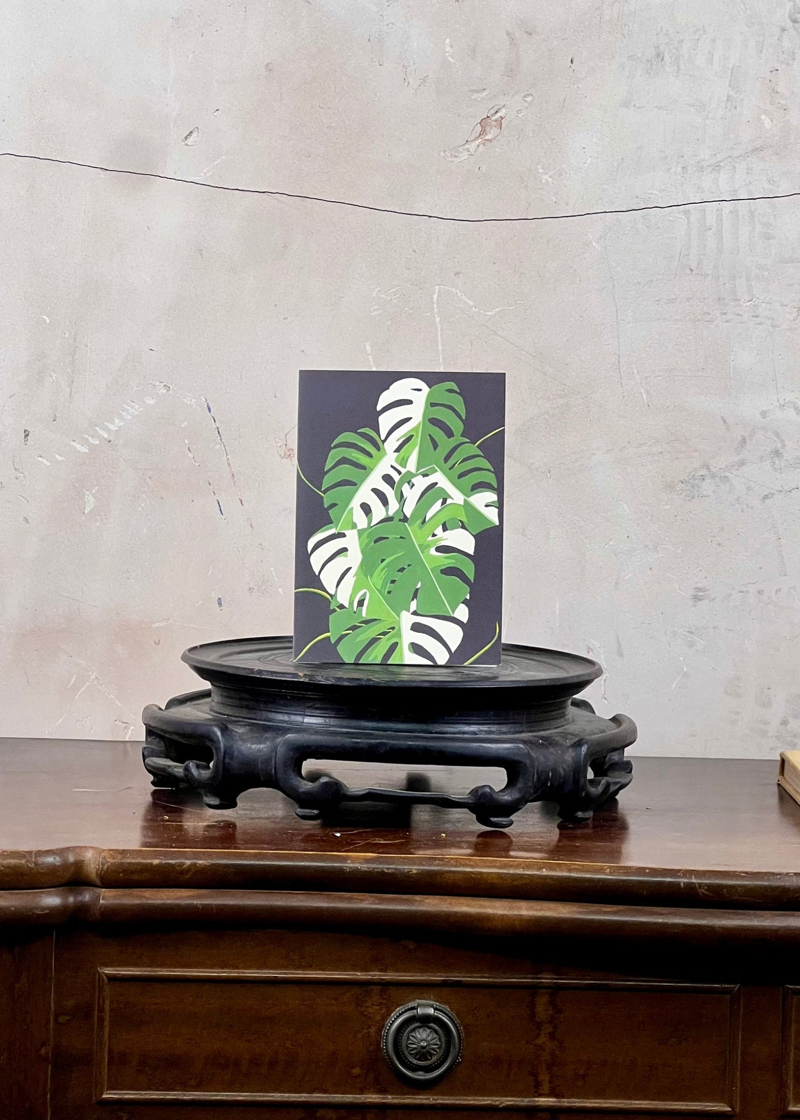 Card with leaf design on a wooden stand against a textured wall