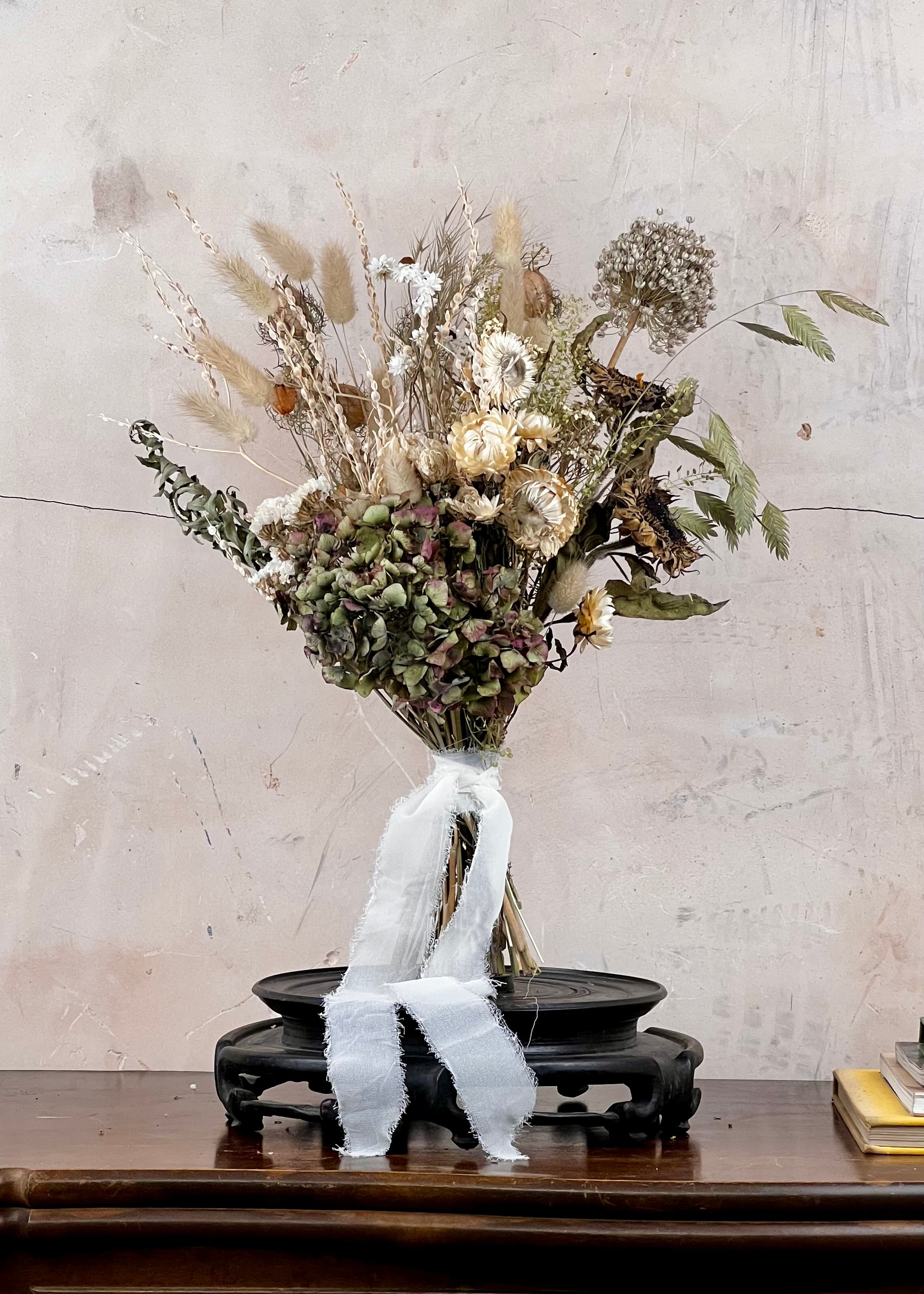 Dried Bridal bouquet of flowers on a wooden table with a textured wall background