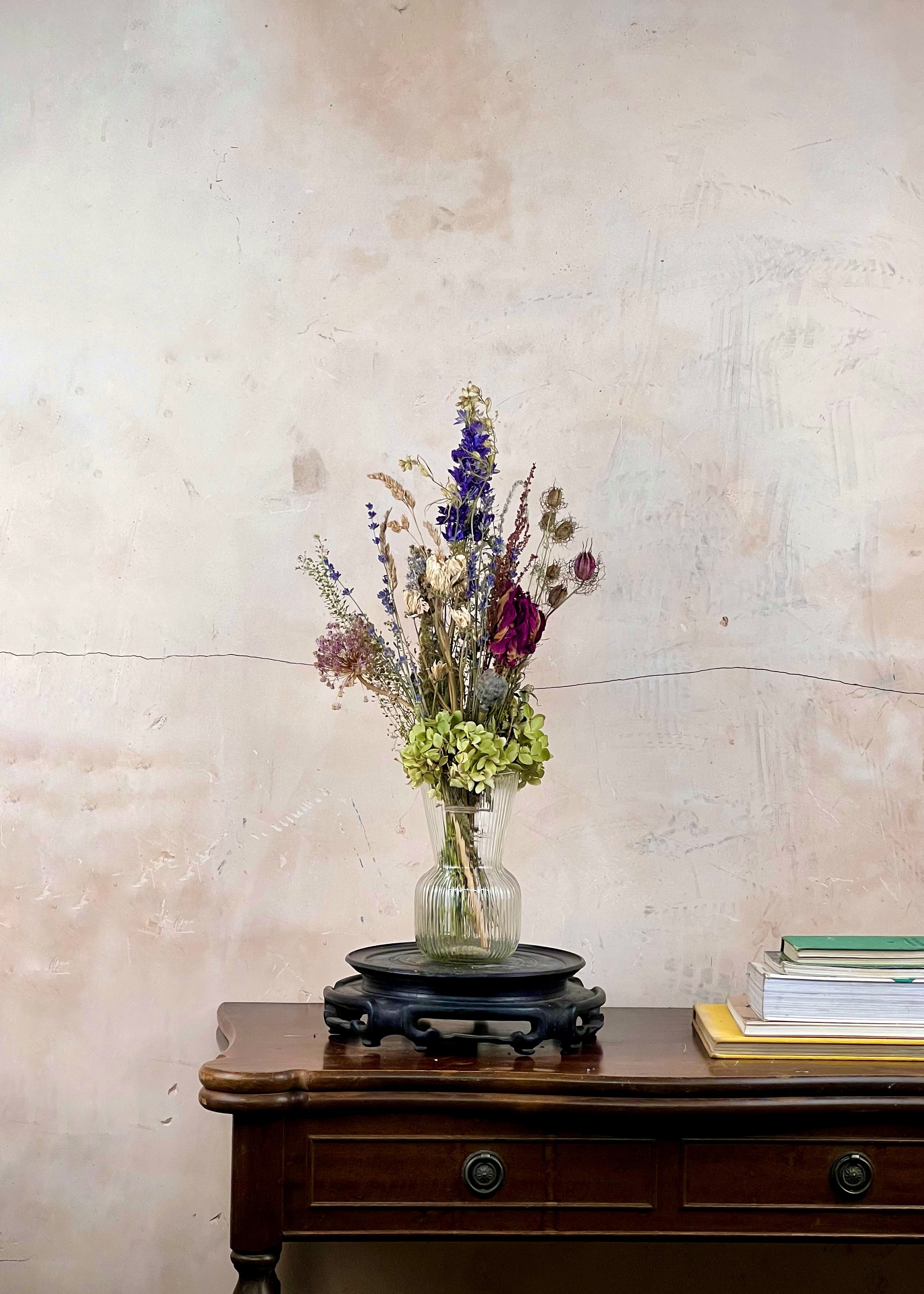 Vase with flowers on a wooden table against a textured wall