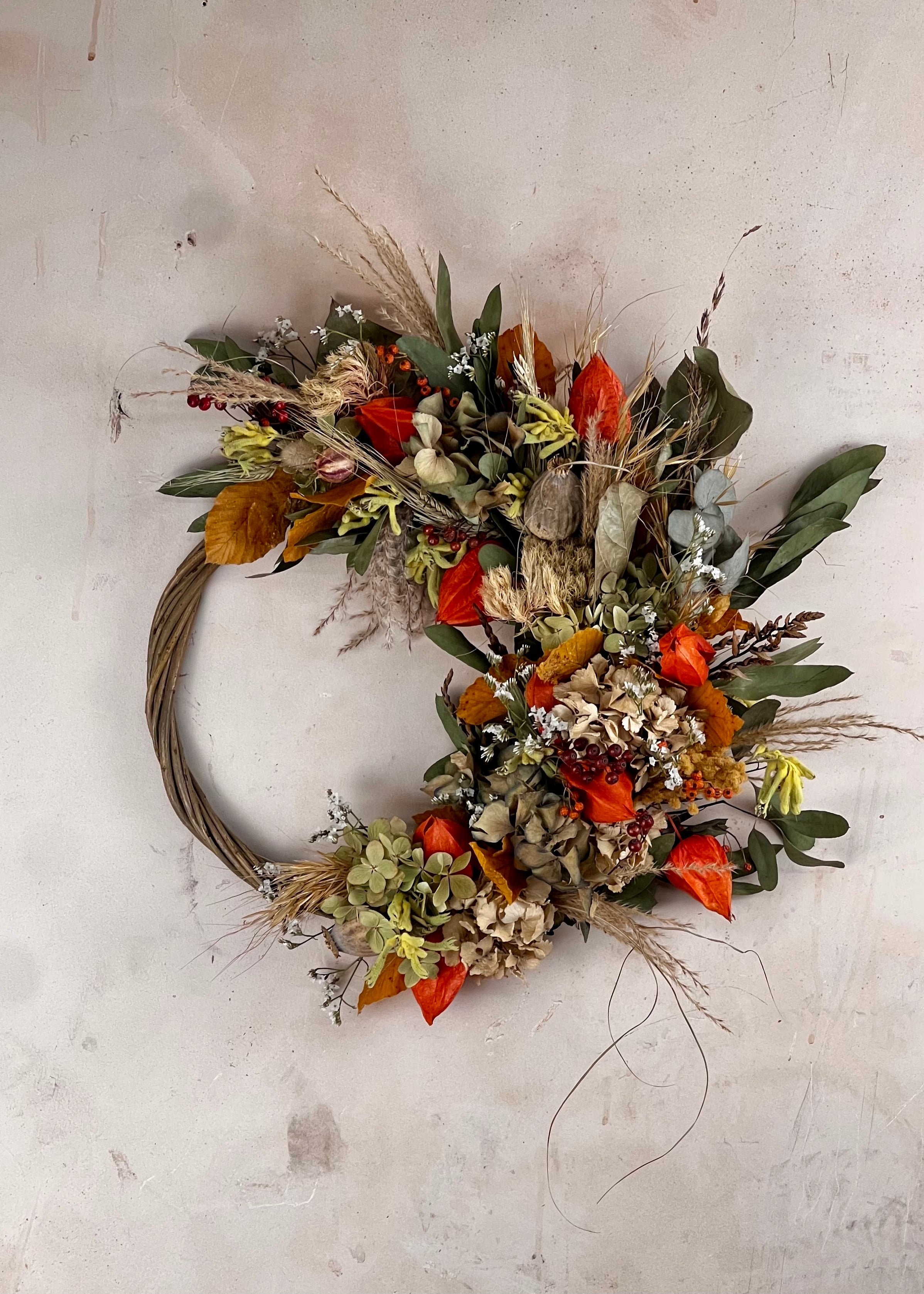 Decorative seasonal dried half wreath with autumnal colors on a textured wall