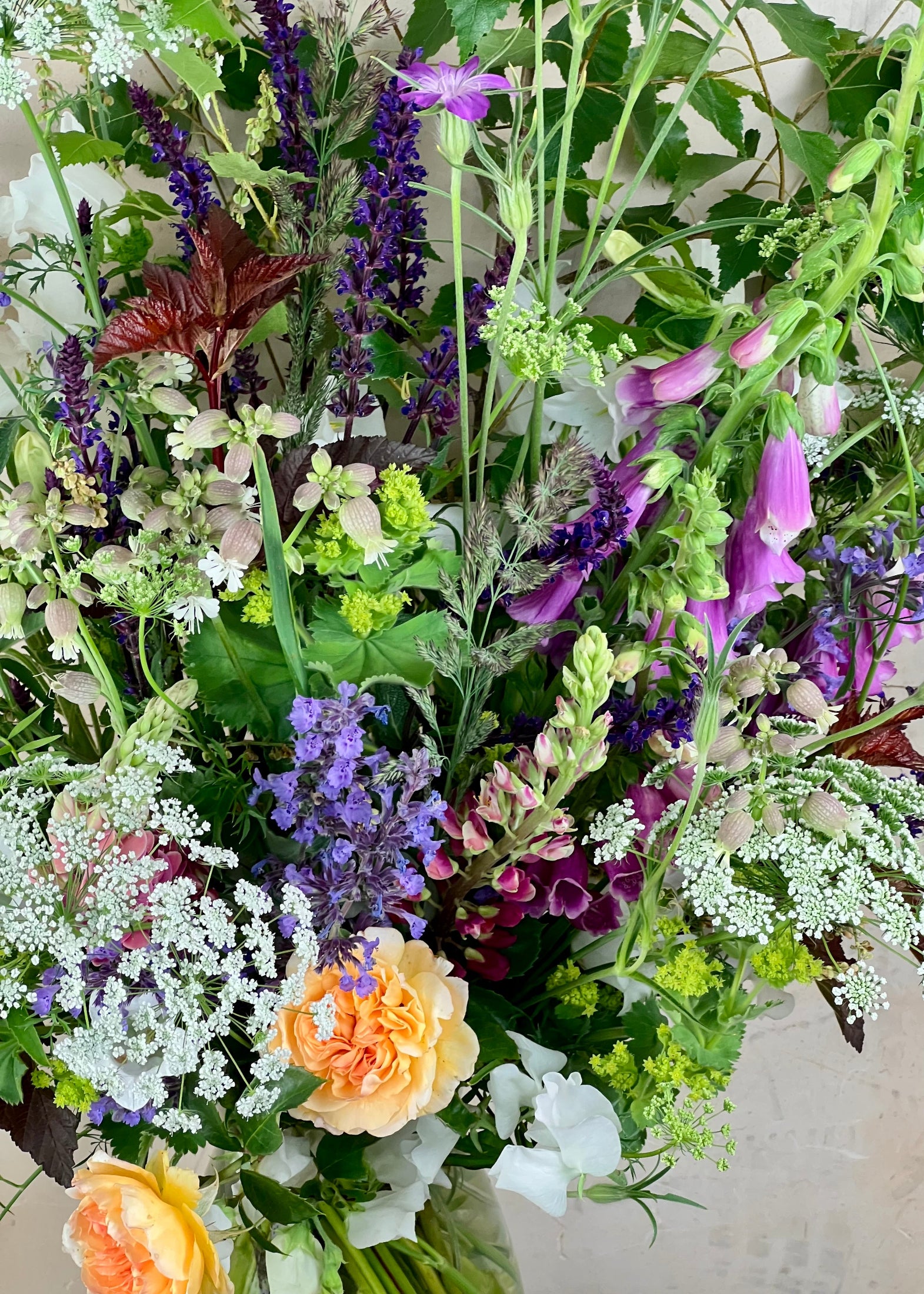 Bouquet of various flowers including purple, white, and orange with green leaves.