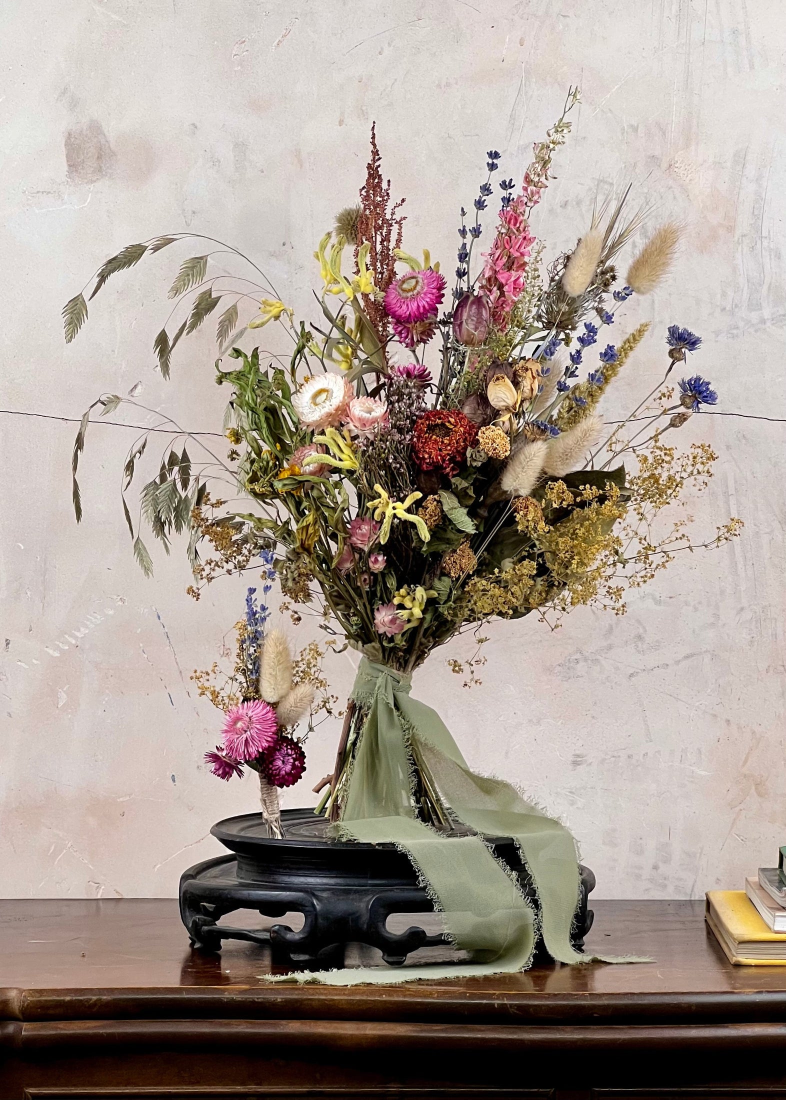 Dried Bridal bouquet of flowers, a matching dried buttonhole on a wooden table with a textured wall background