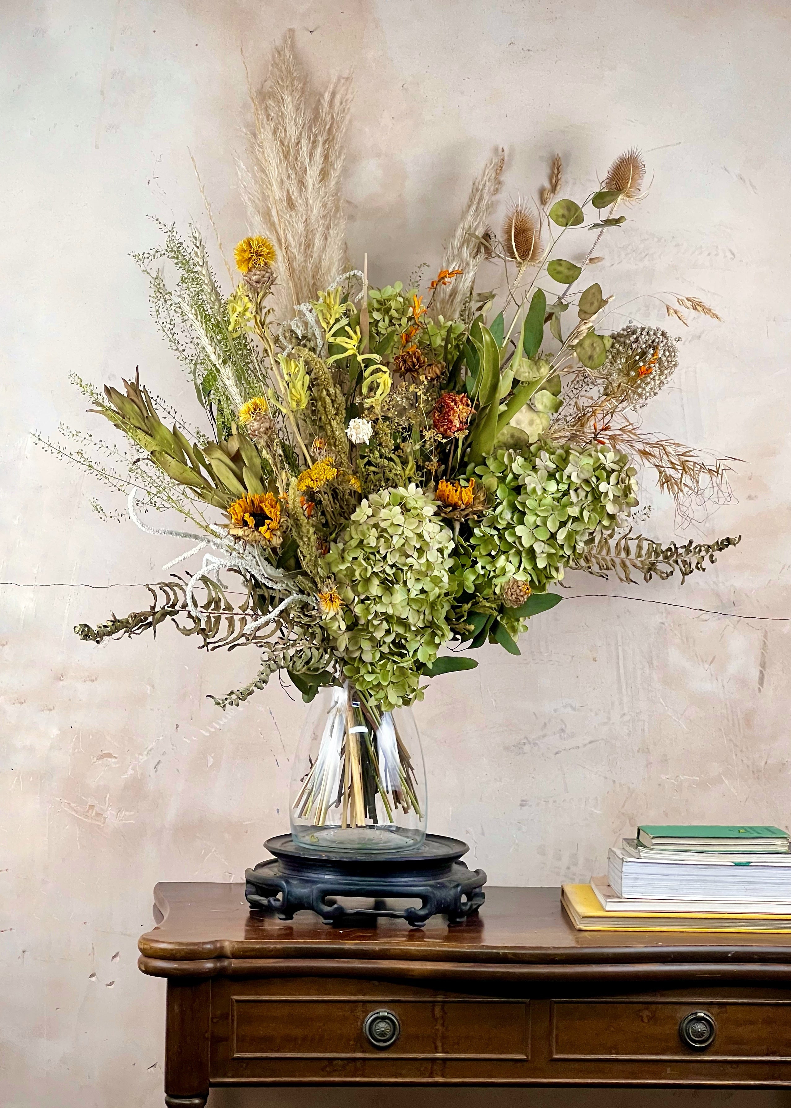Bouquet of flowers in a clear vase on a wooden table with a neutral background