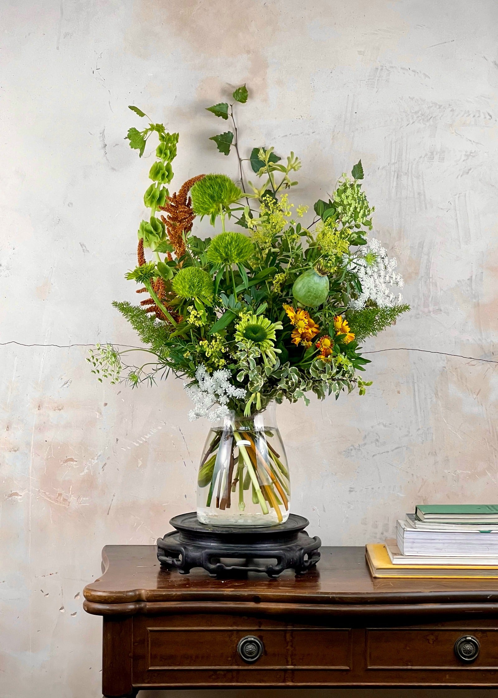 Vibrant floral arrangement in a clear vase on a wooden table with a textured wall background