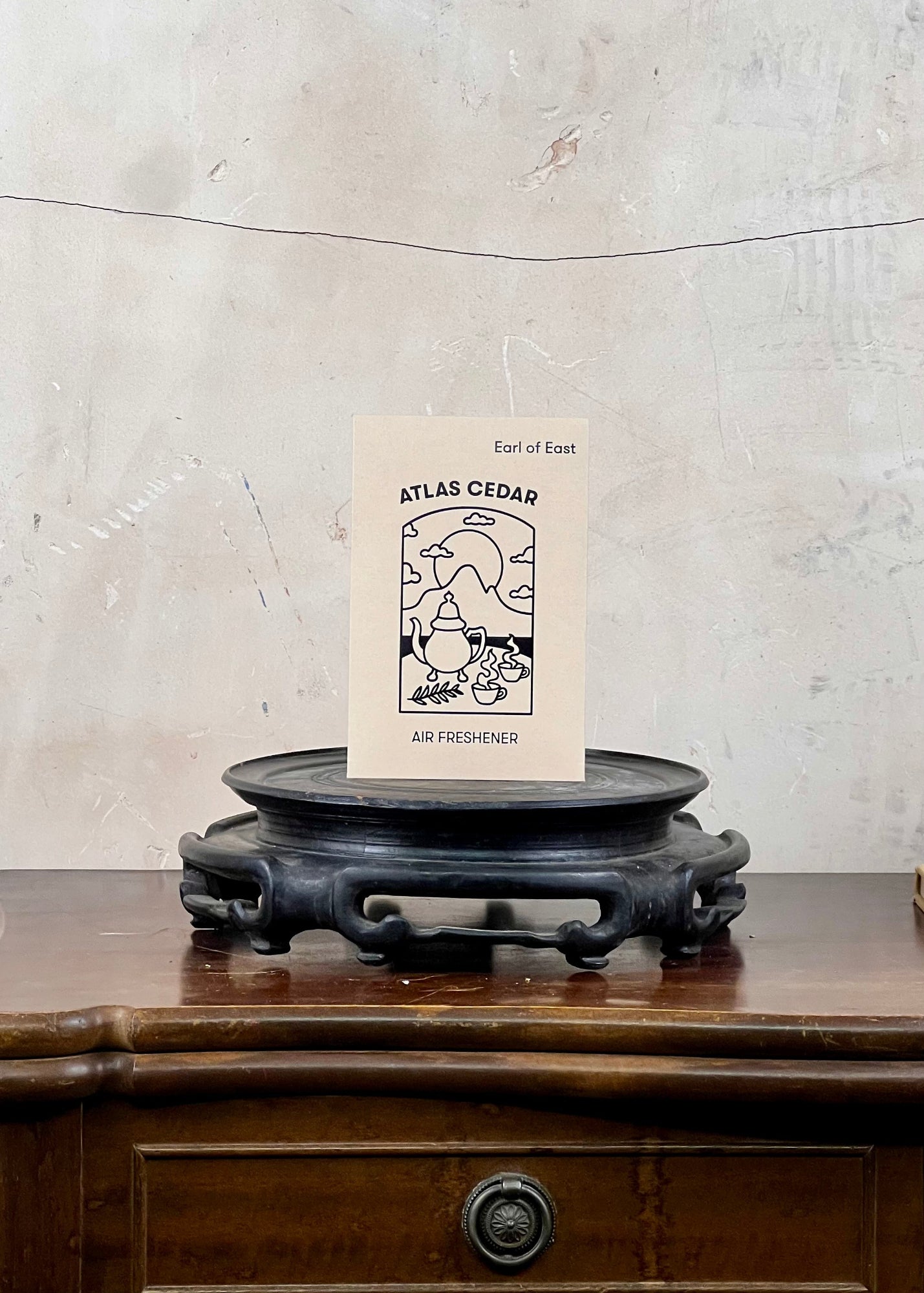 Air freshener packaging on a wooden surface with a textured wall background