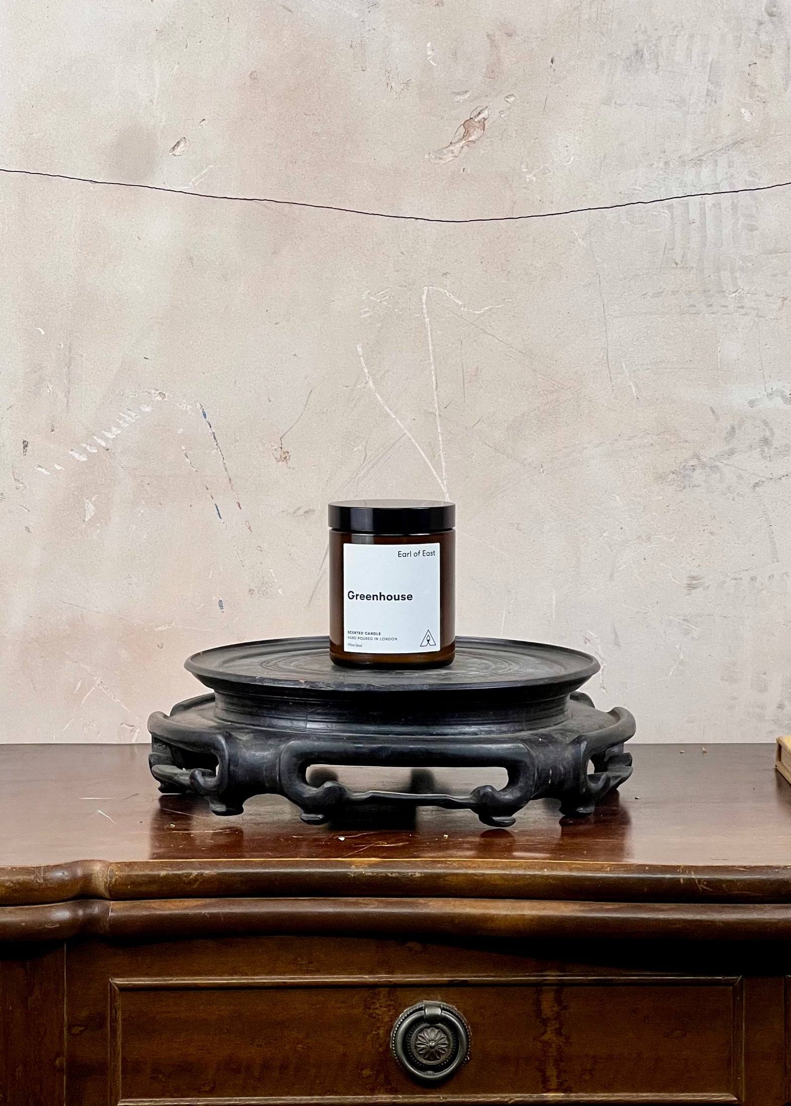 Candle on a wooden stand with a marble wall background